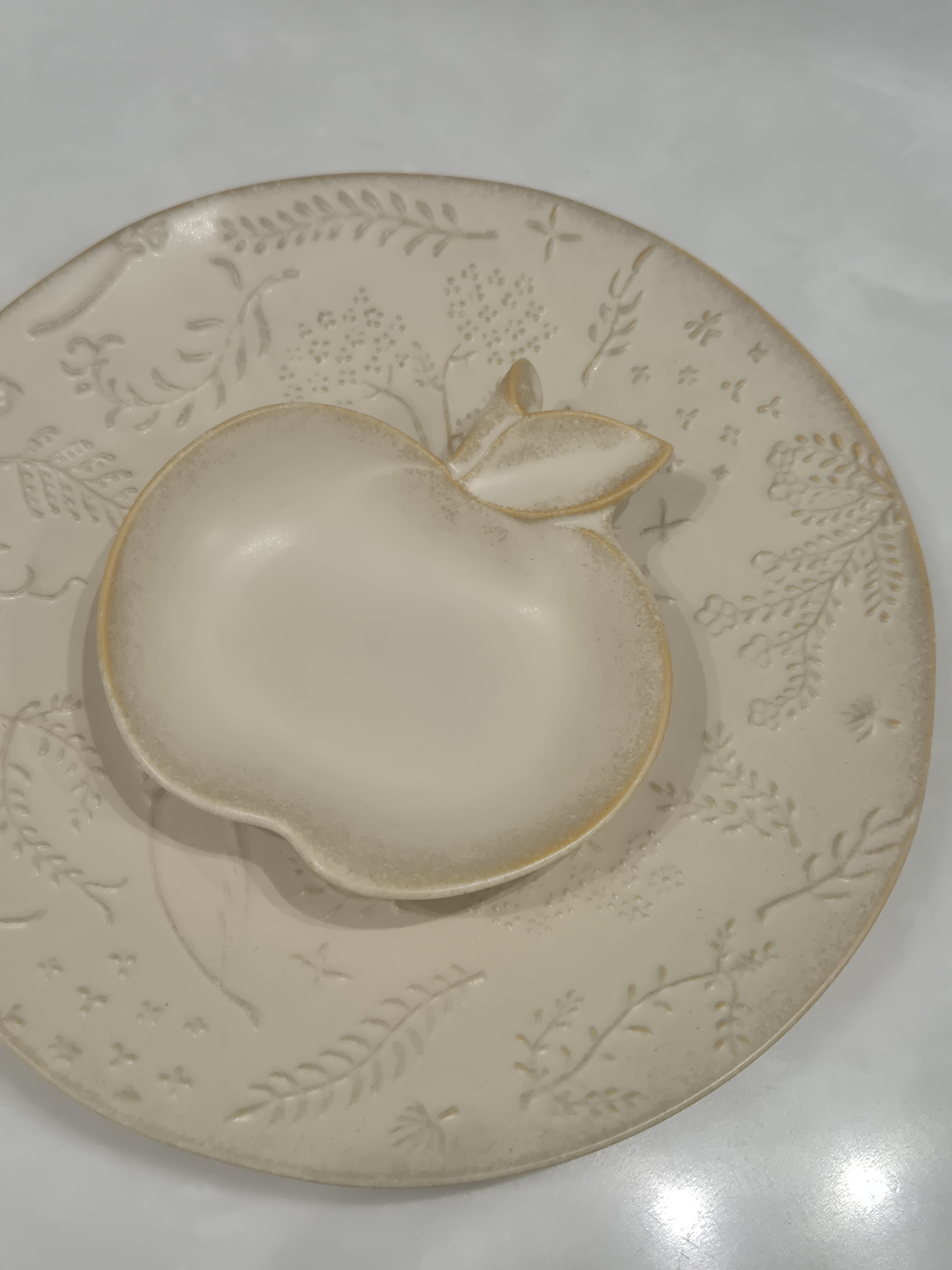 Apple-shaped ceramic plate with floral details.