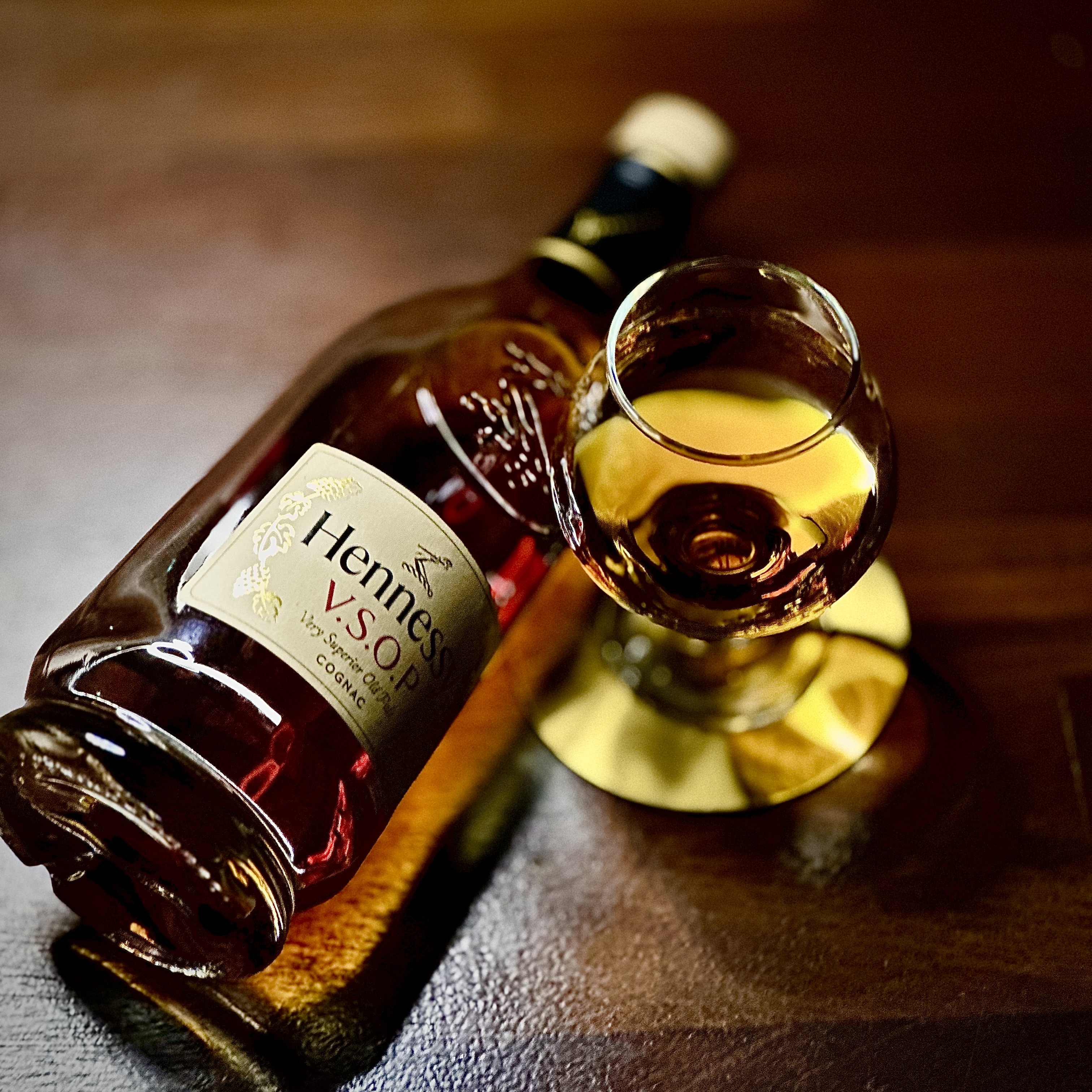A bottle of Hennessy VSOP cognac and a snifter glass on a wooden table