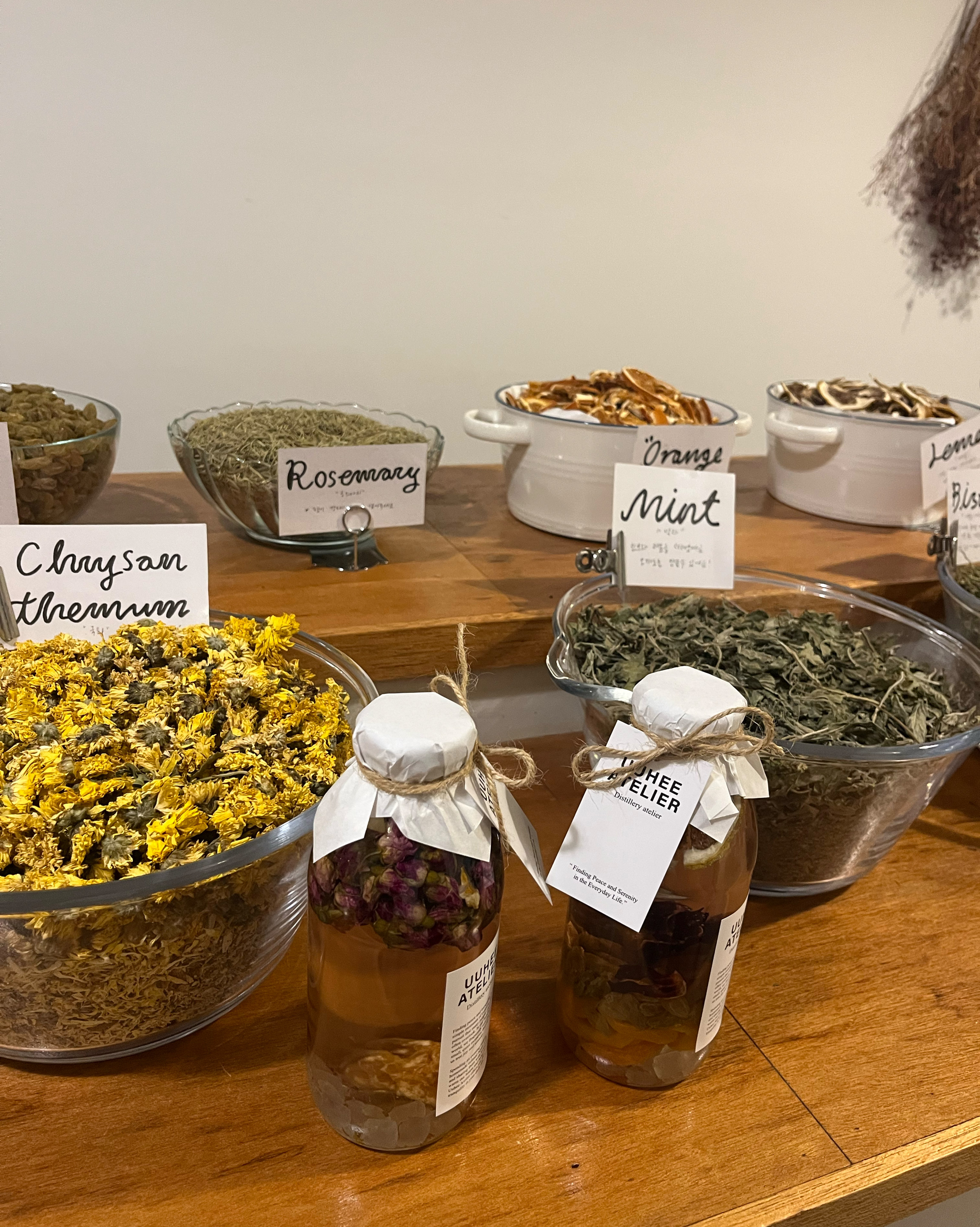 Curated glass bowls of dried botanicals, chrysanthemums, and infused bottles.
