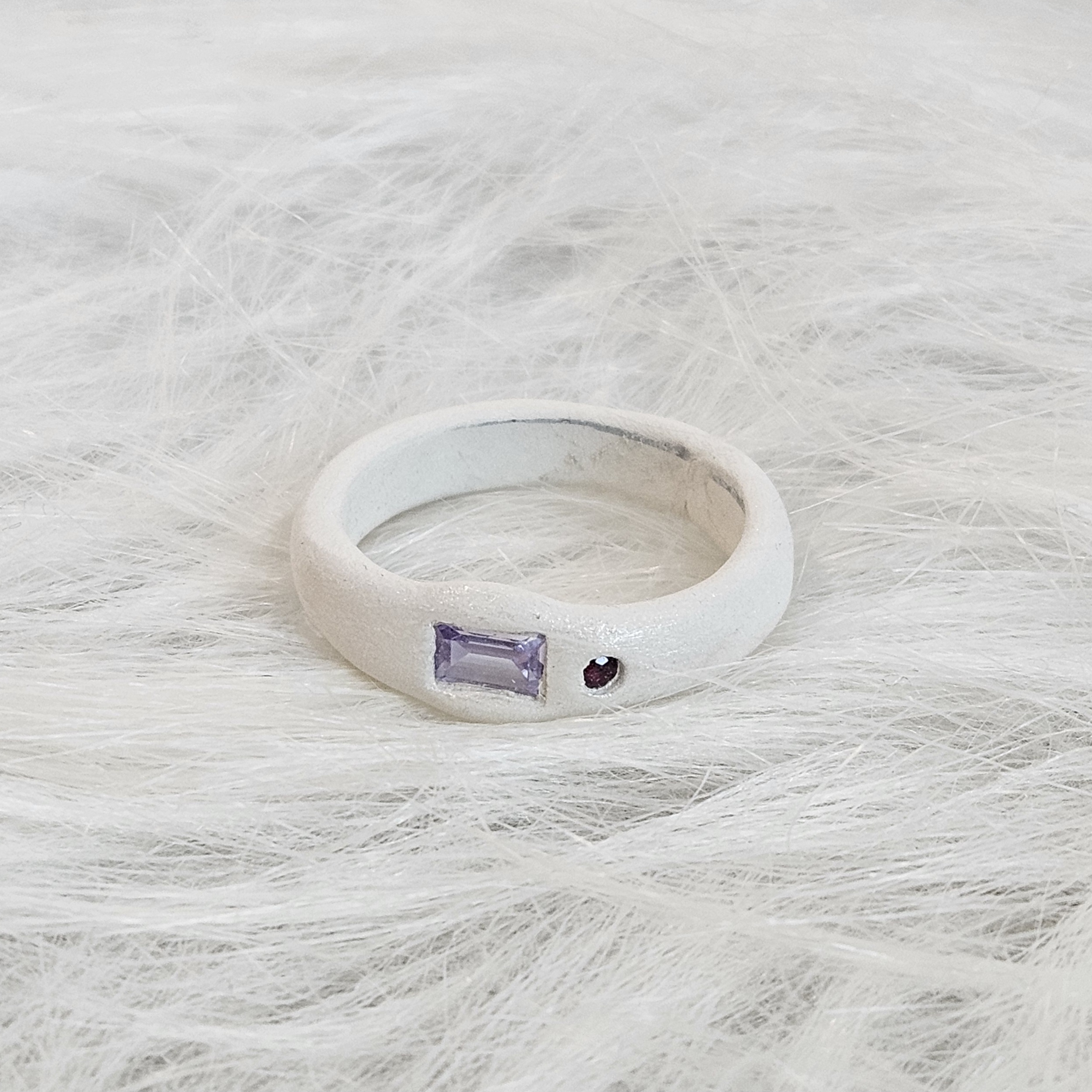 Premium silver ring featuring delicate gemstone accents on a textured surface