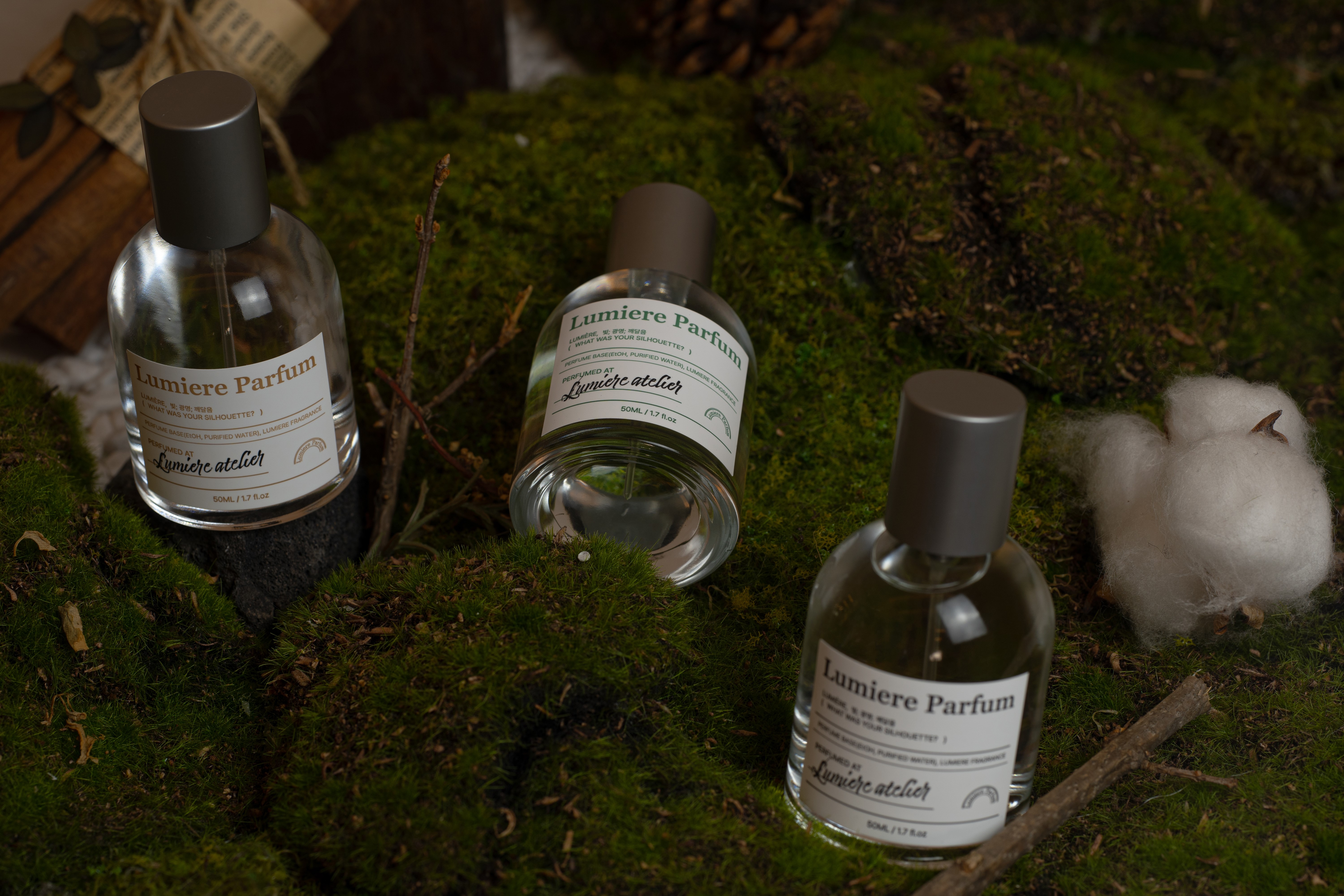 Three bottles of Lumiere Parfum displayed on natural botanical moss