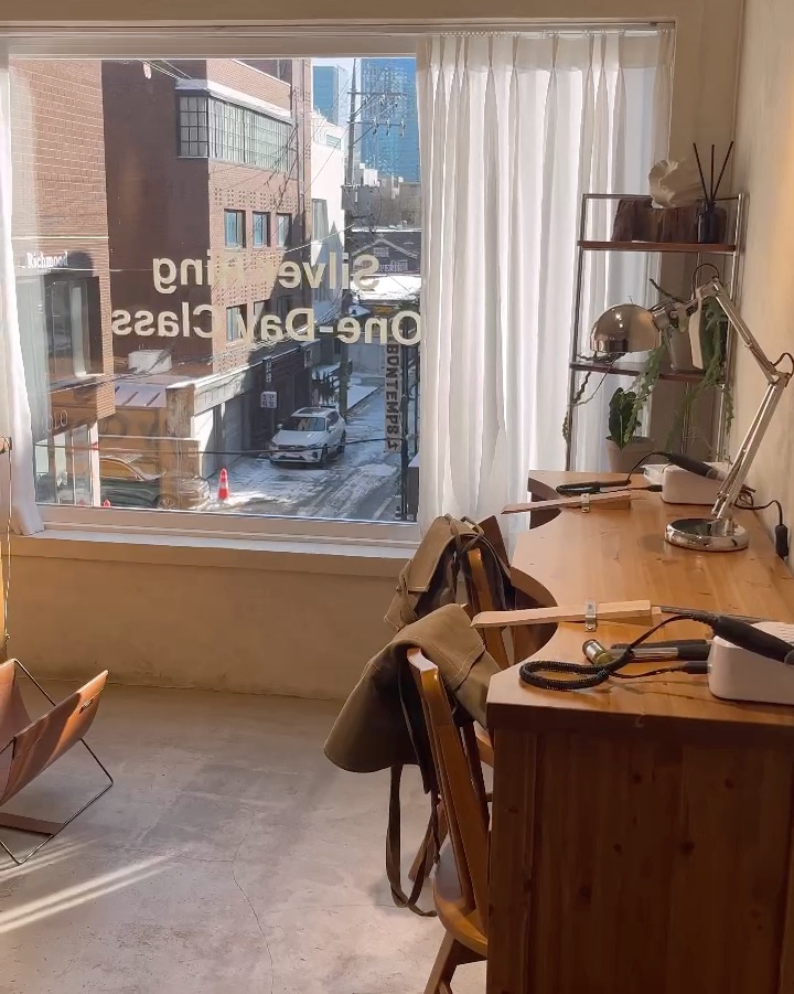 Sunlit jeweler desk positioned by large windows overlooking Seongsu streets