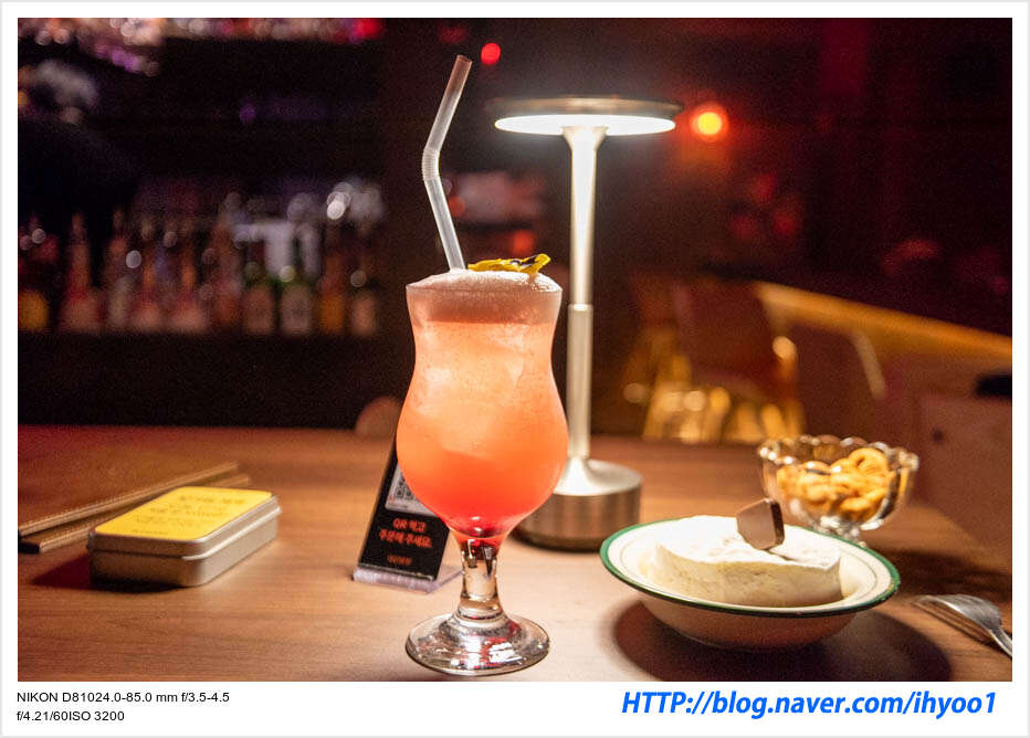 Cocktail glass and cheese bite on a wooden bar counter