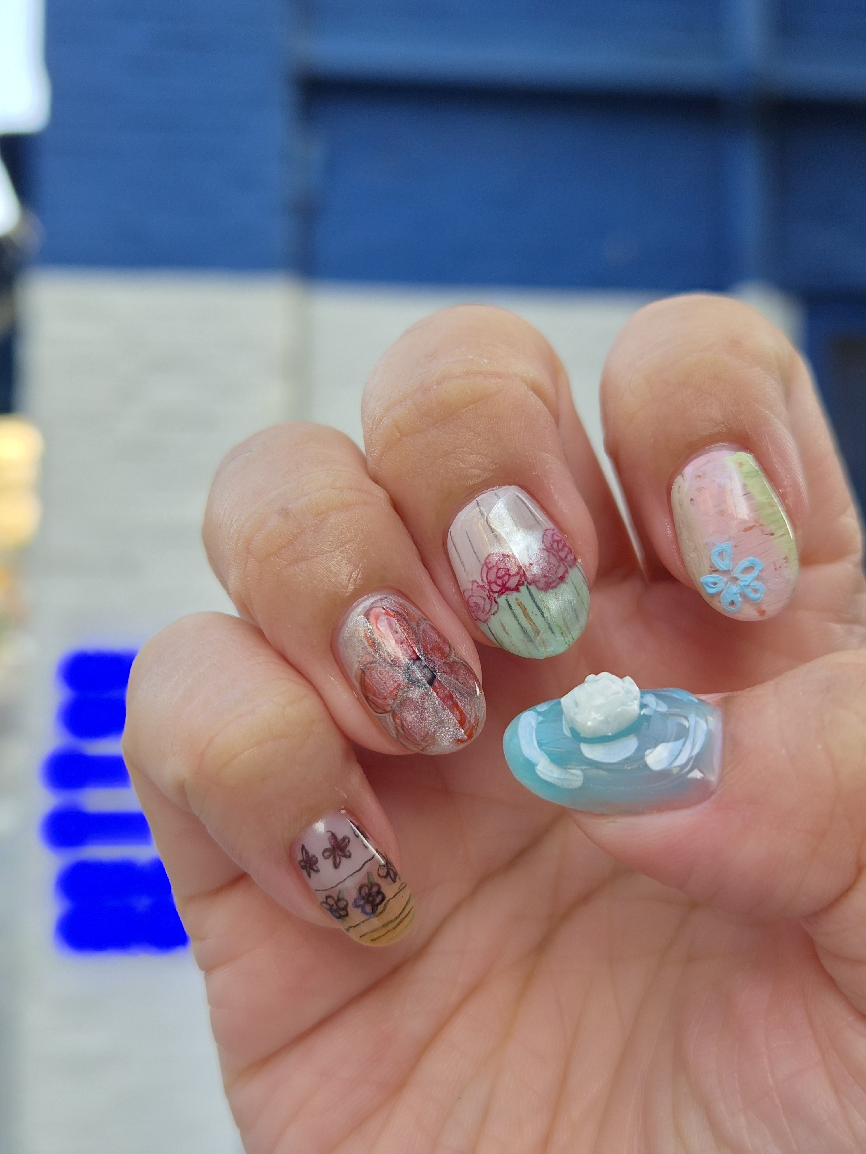 Close-up of hand showcasing intricate floral and abstract nail art designs