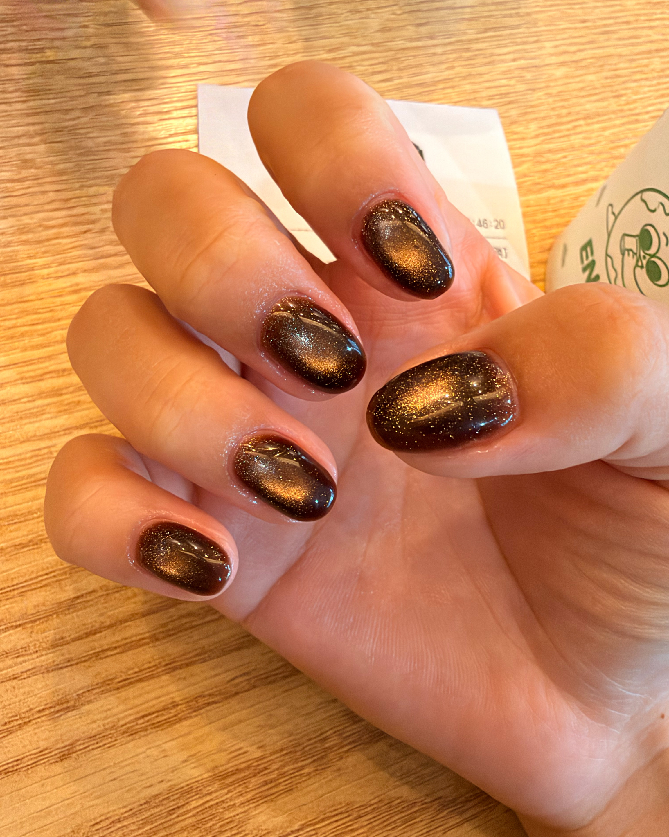 Deep brown magnetic cat-eye gel nail set with golden shimmer highlights