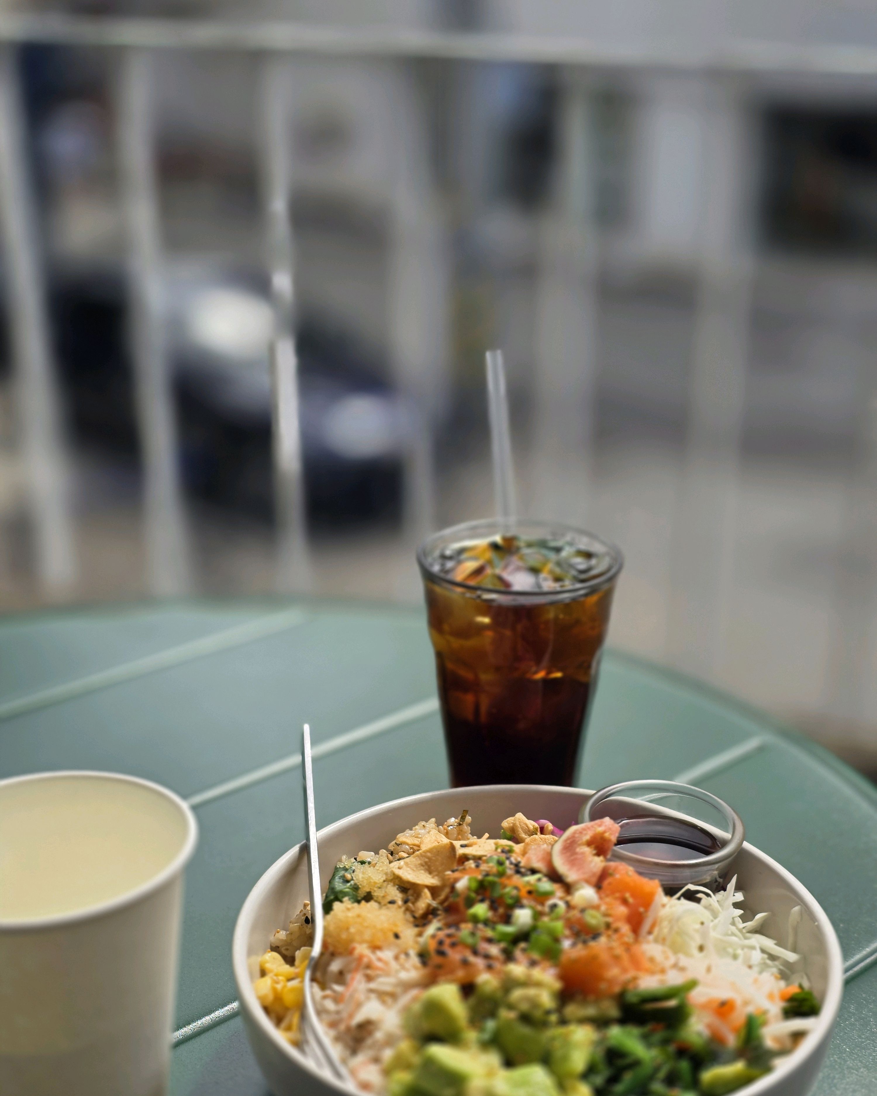 Poke bowl and iced beverage enjoyed on the outdoor terrace table