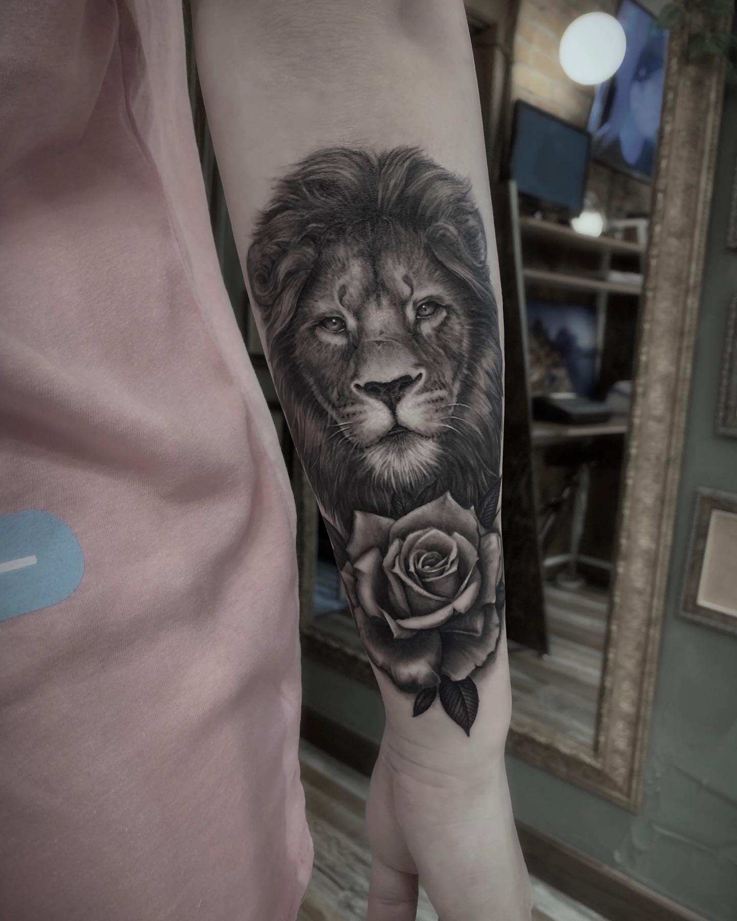 Close-up of a realistic lion and rose tattoo on a person's forearm.