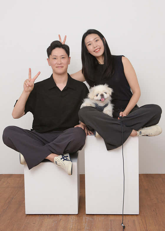 Couple posing with their white dog on studio pedestals
