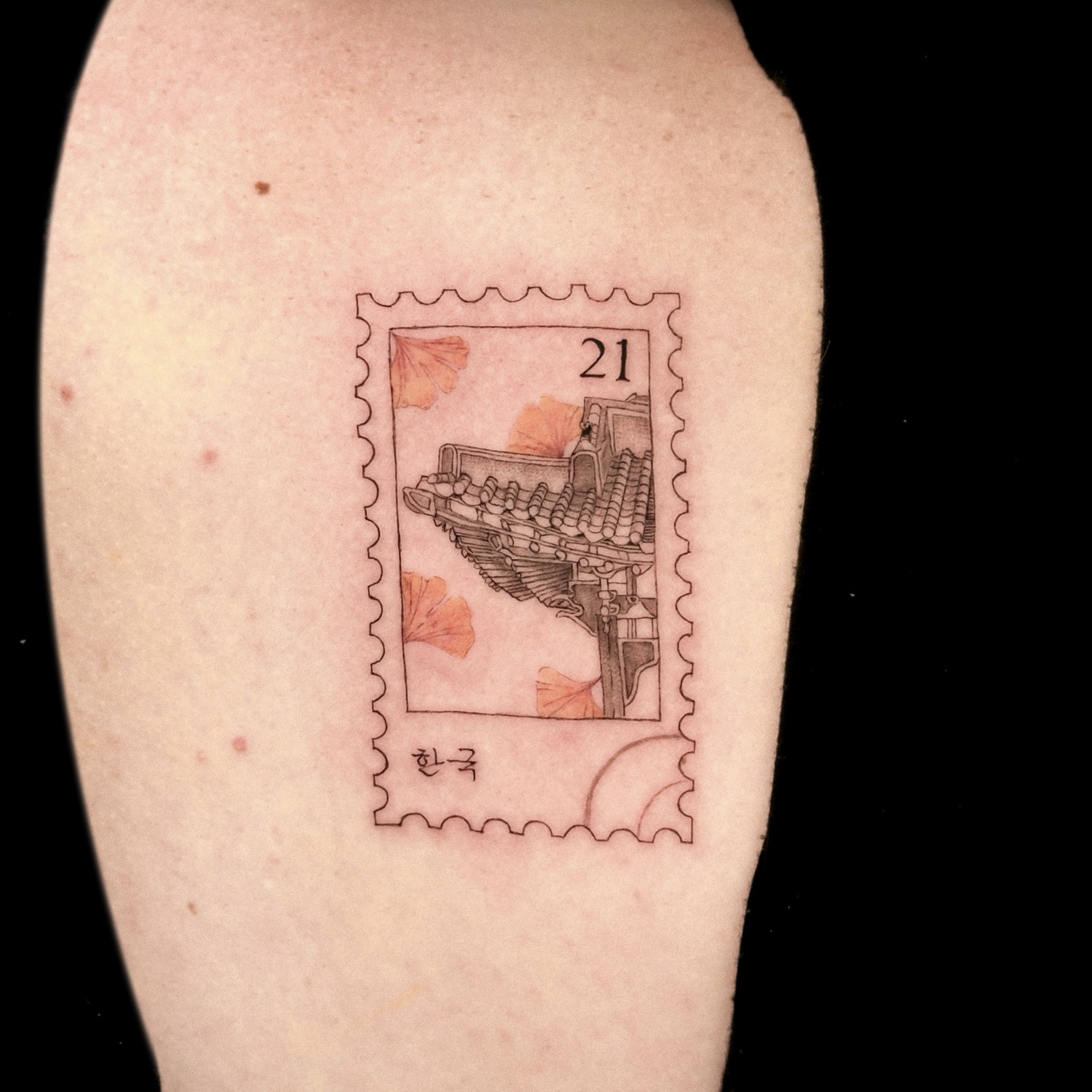 Stamp-shaped fine line tattoo featuring traditional Korean roof and ginkgo leaves