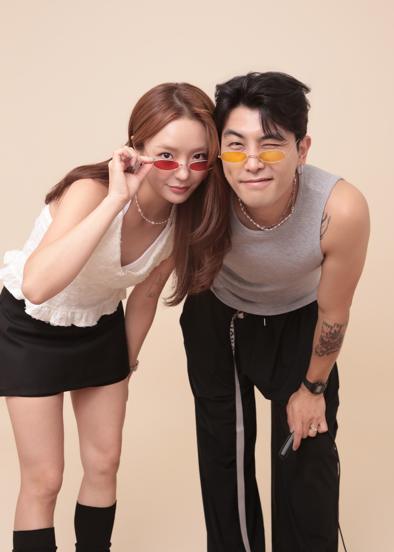 Two people posing with sunglasses in studio