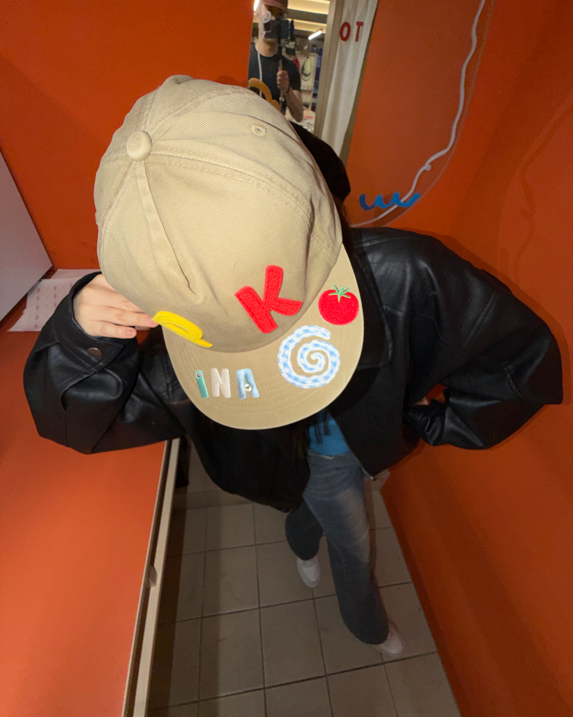 Customer wearing beige cap decorated with colorful felt letters and graphic patches