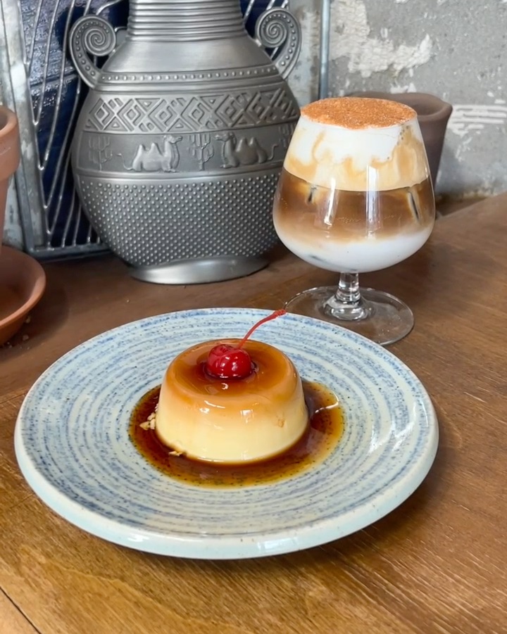 Layered iced coffee in stemmed glassware alongside custard pudding