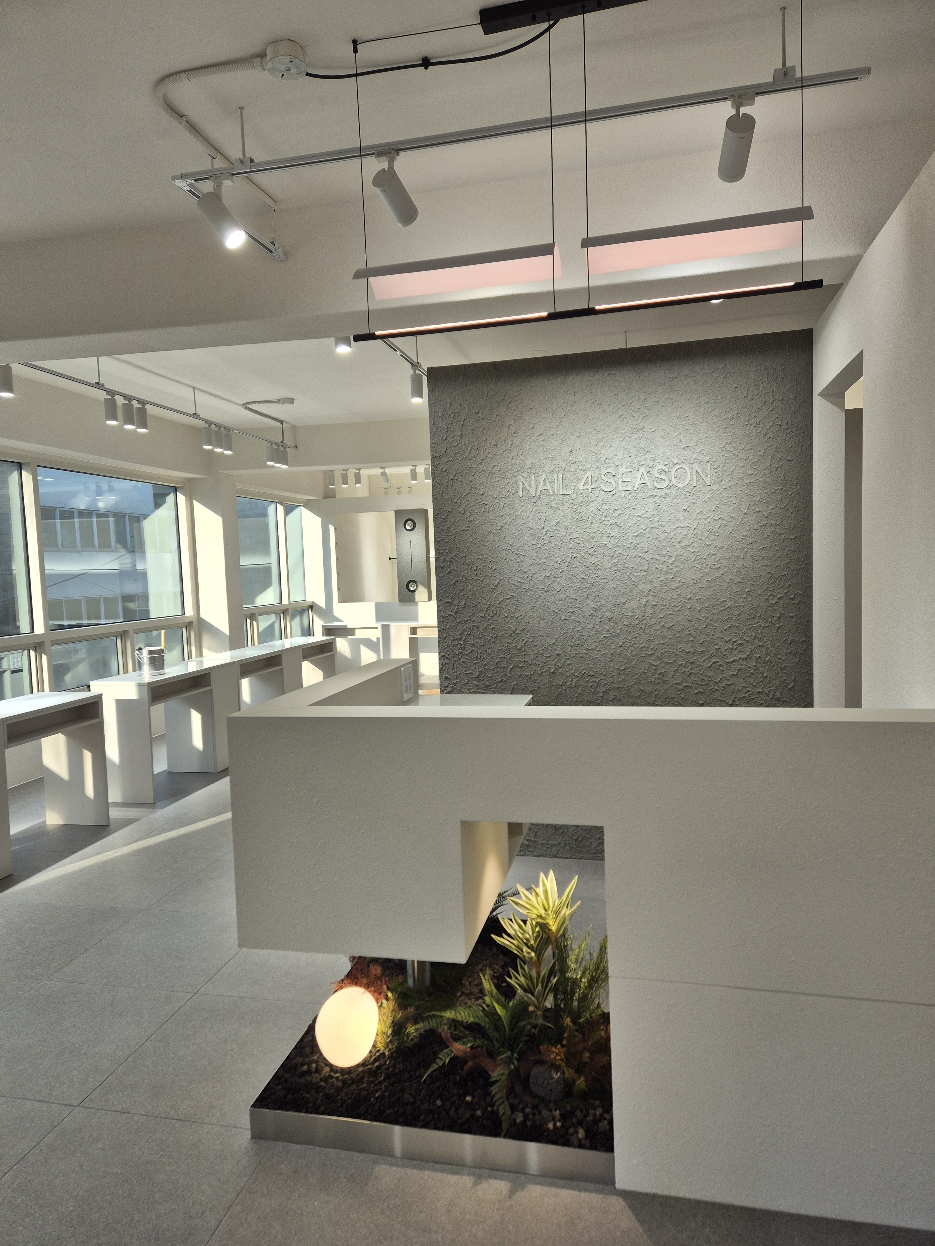 Reception desk with indoor garden installation and textured minimalist wall