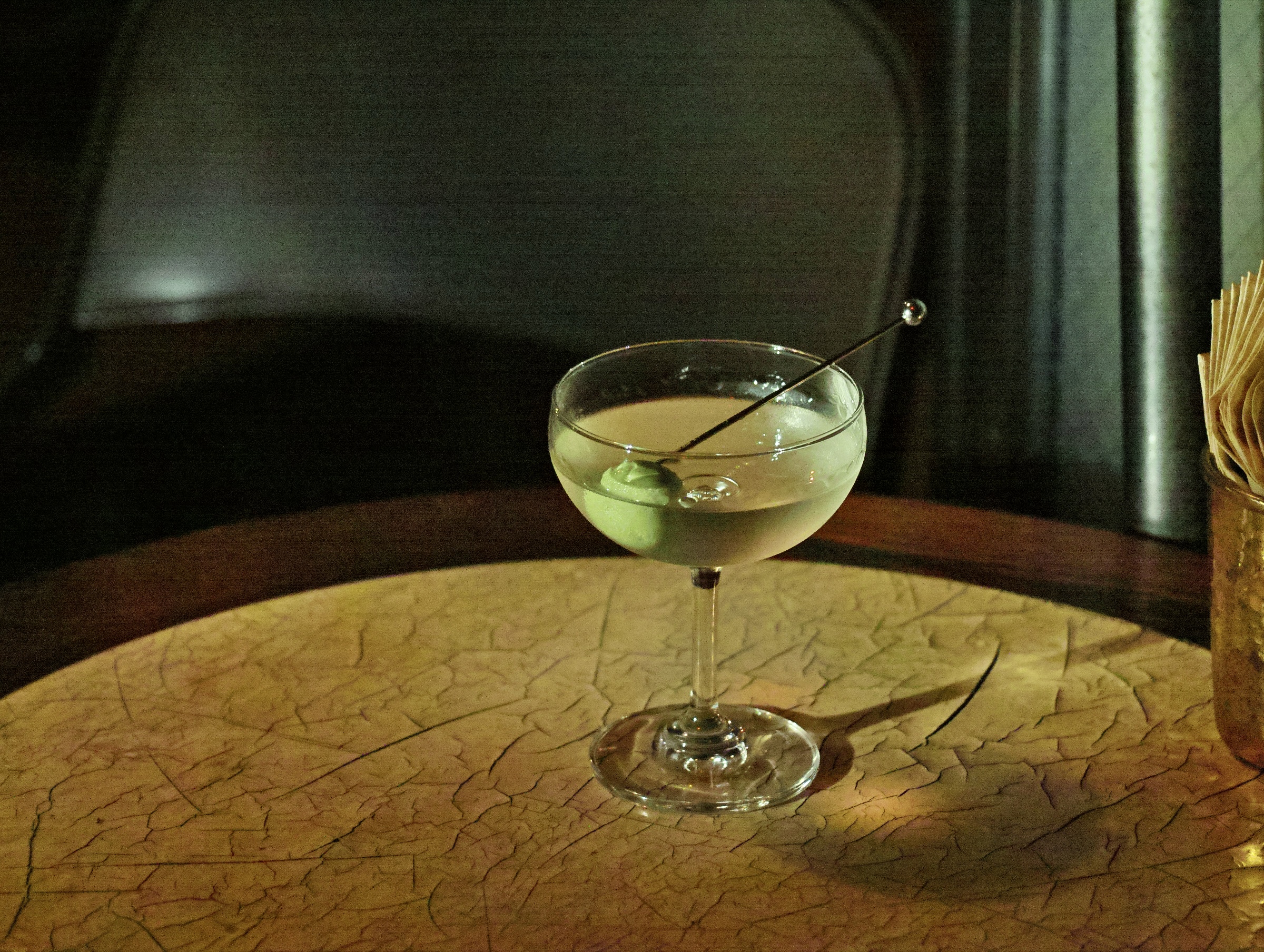 Chilled craft cocktail in a coupe glass served on a textured stone table.