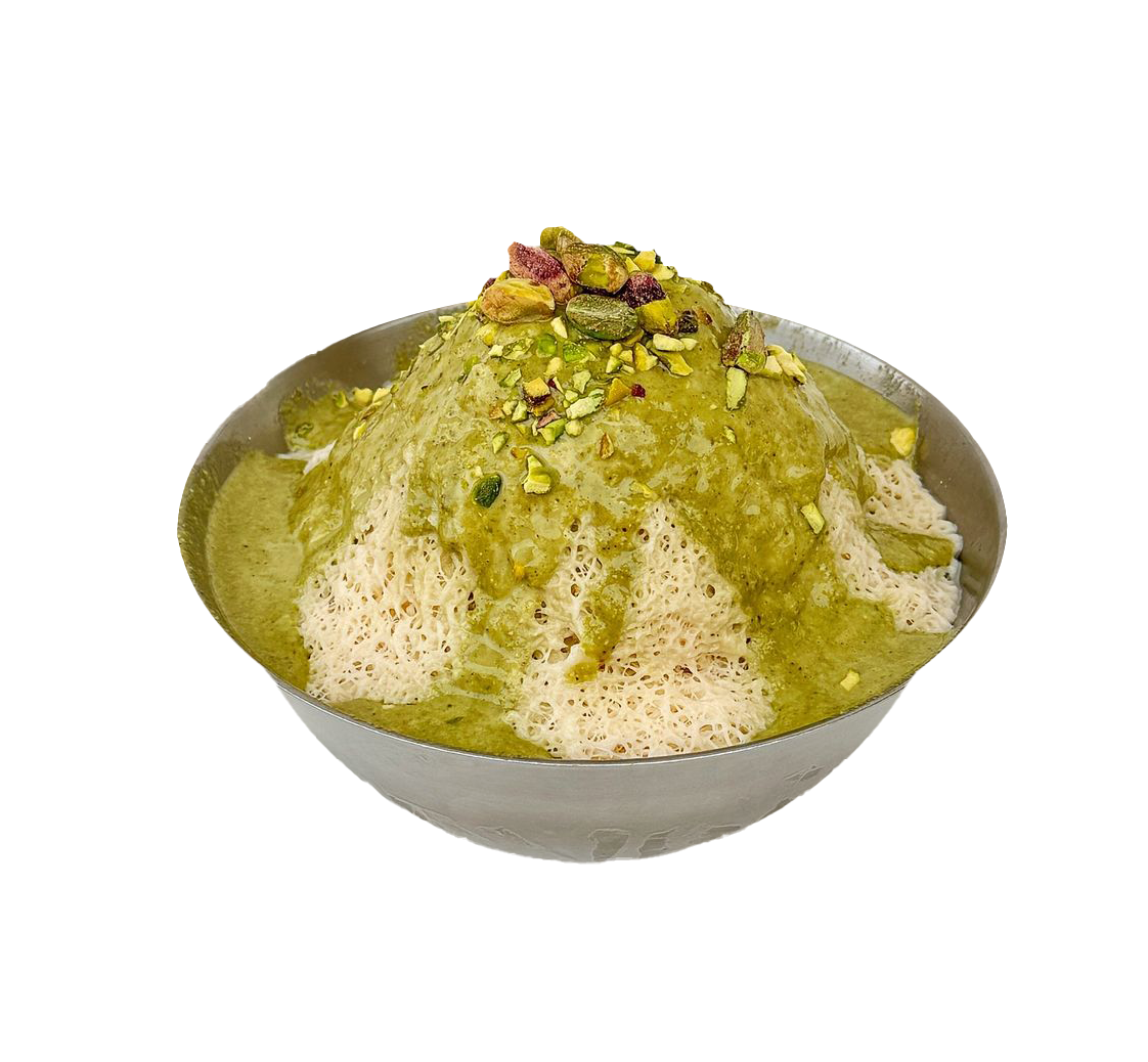 A metal bowl filled with shaved ice topped with green pistachio sauce and chopped pistachio nuts against a black background.