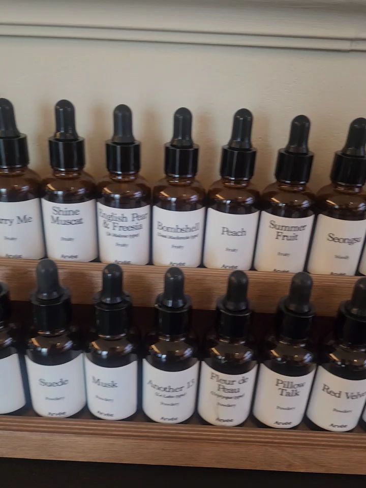 Two tier wooden rack holding labeled amber essence dropper bottles