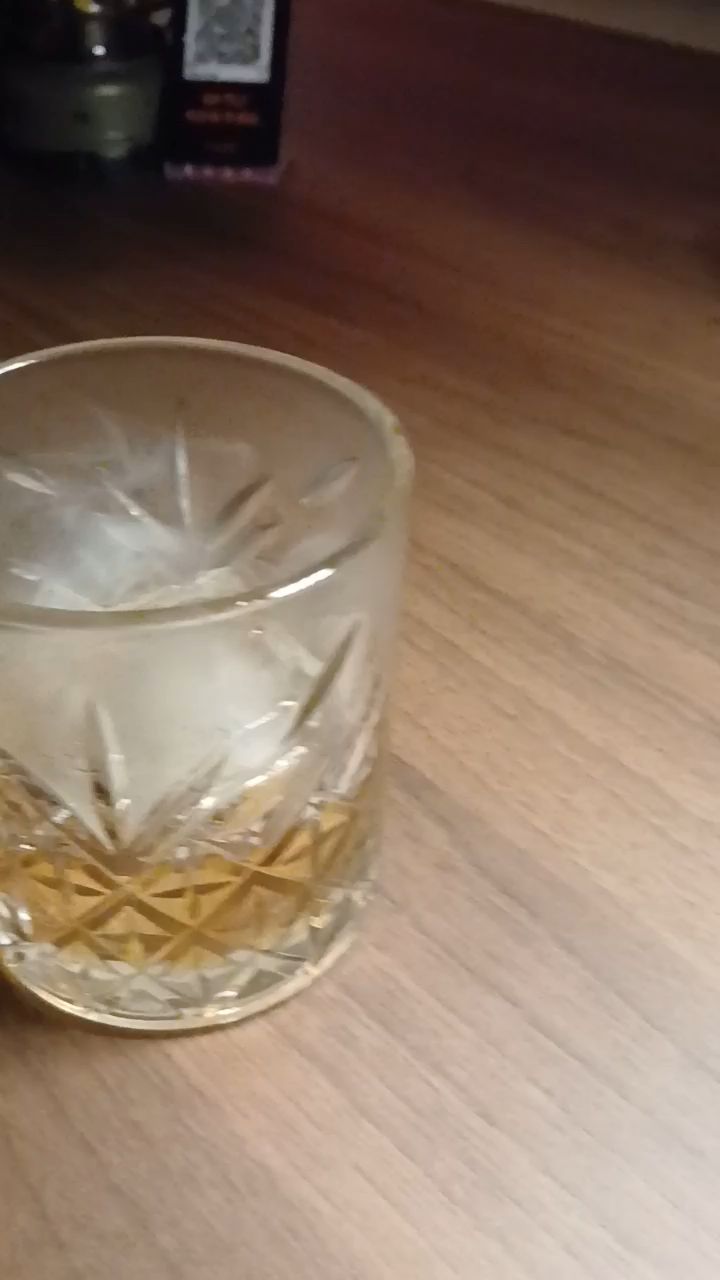 Cut crystal rocks glass with whiskey on dark wood counter