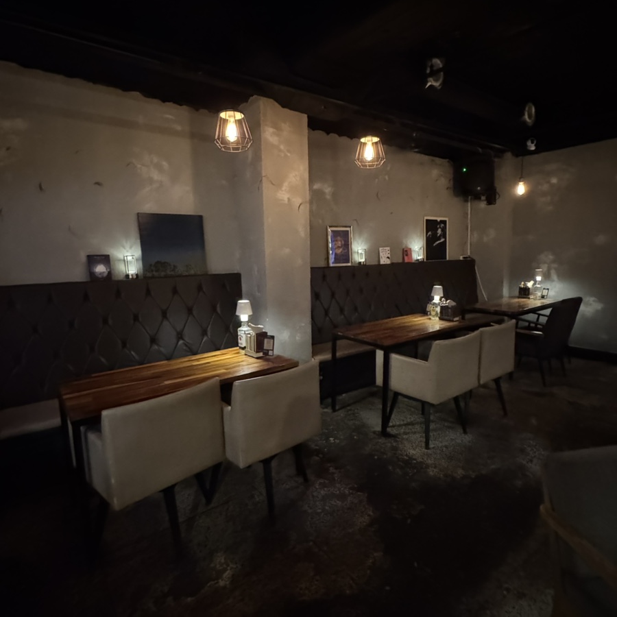 Dimly lit pub interior with dark tufted booth seating and warm pendant lighting