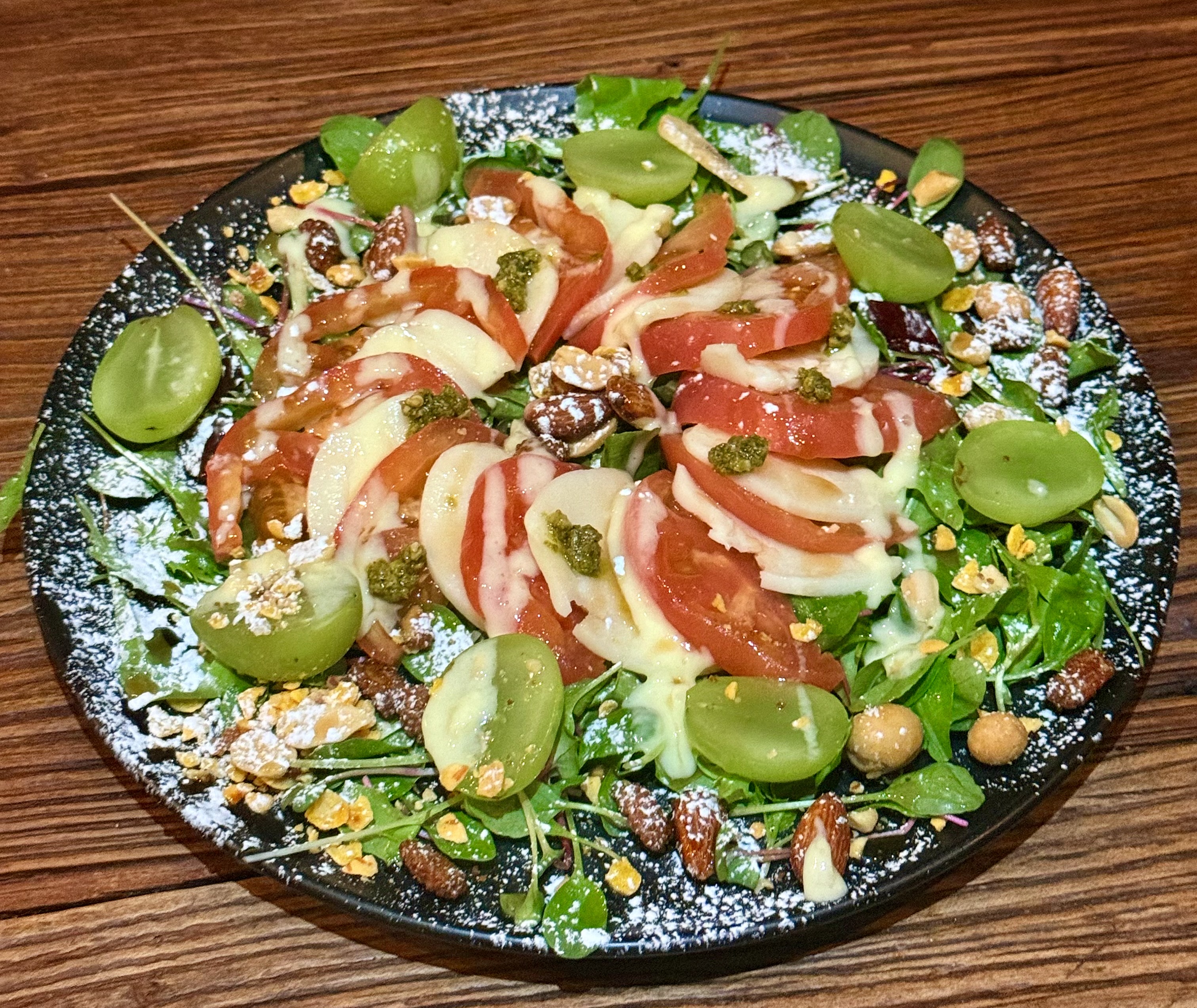 Caprese salad plate with tomatoes, cheese, grapes, and nuts