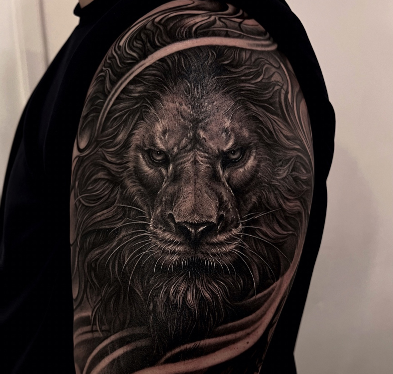 Close-up of a detailed lion head tattoo on a person's upper arm.