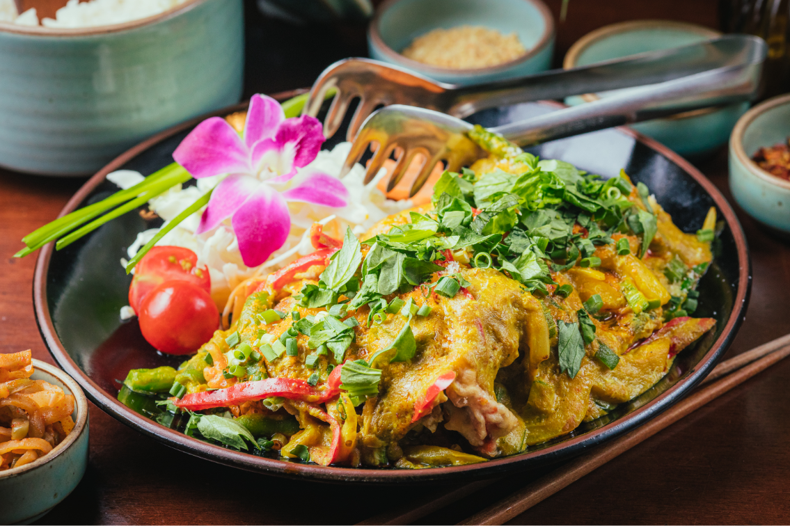 Yellow curry garnished with fresh herbs and orchid flower