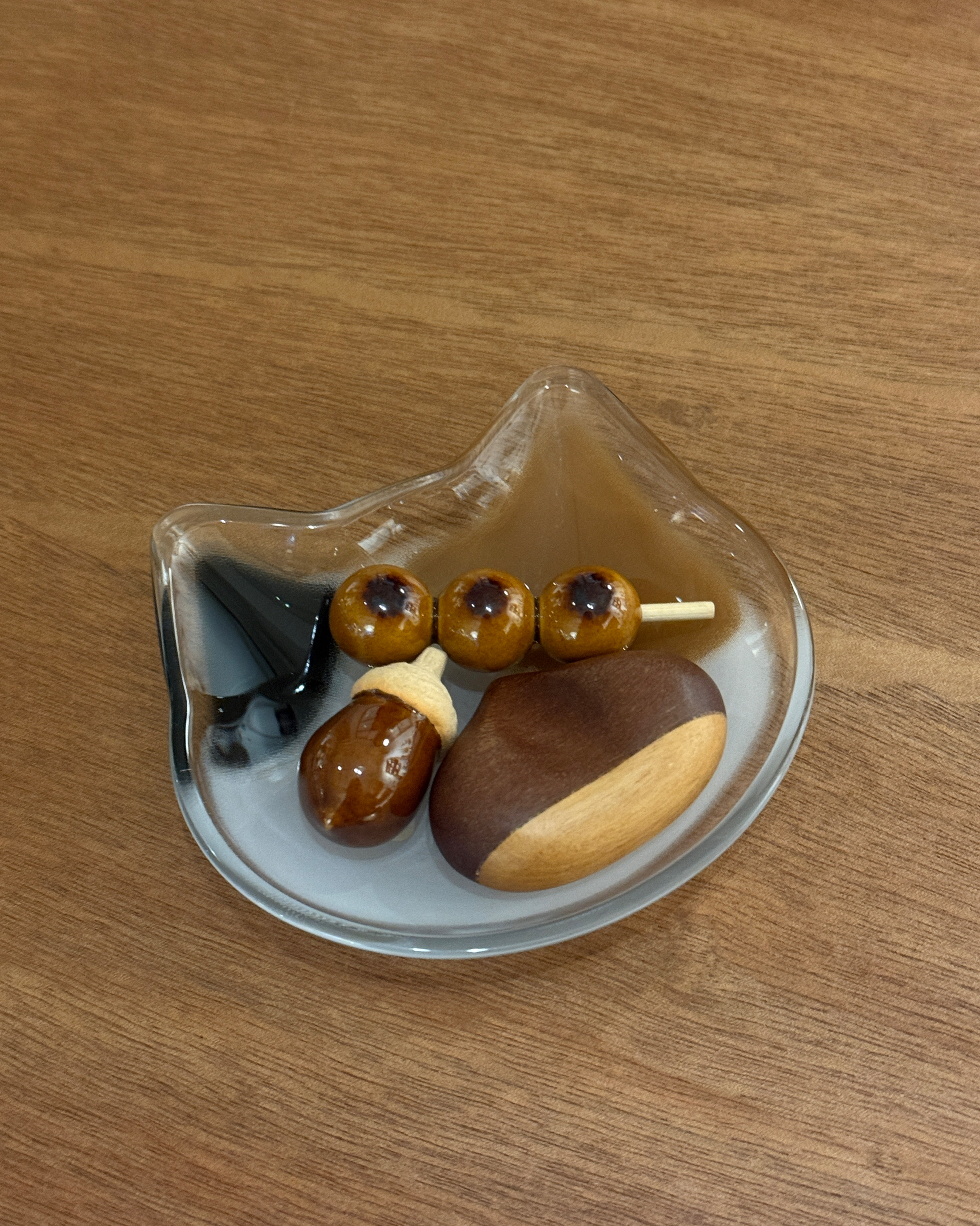 Miniature dango and acorn figurines on a glass tray.