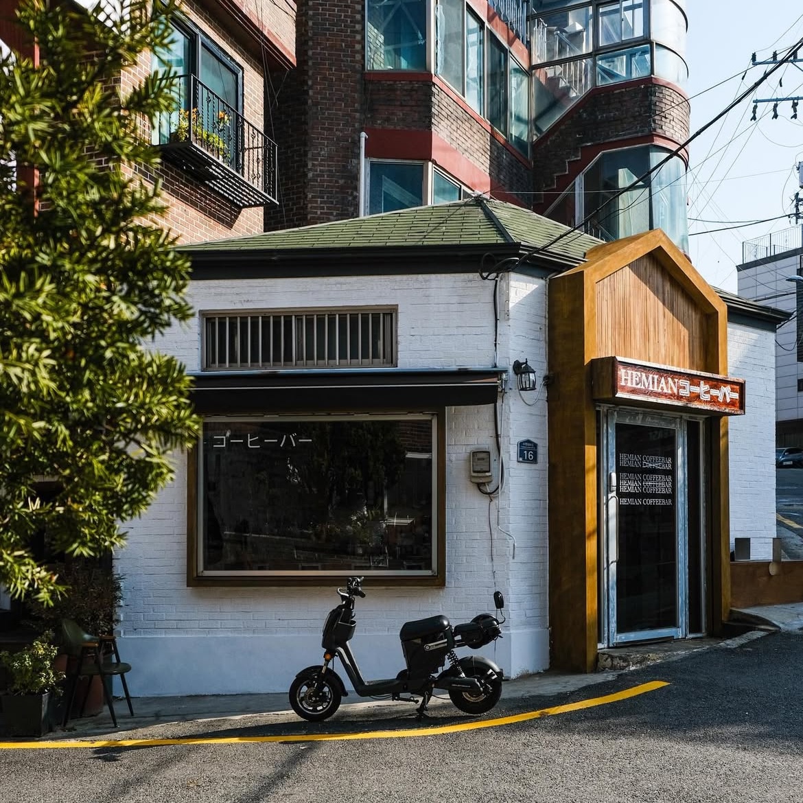 Exterior view of Hemian Coffee Bar with white brick walls and dark green gabled roof