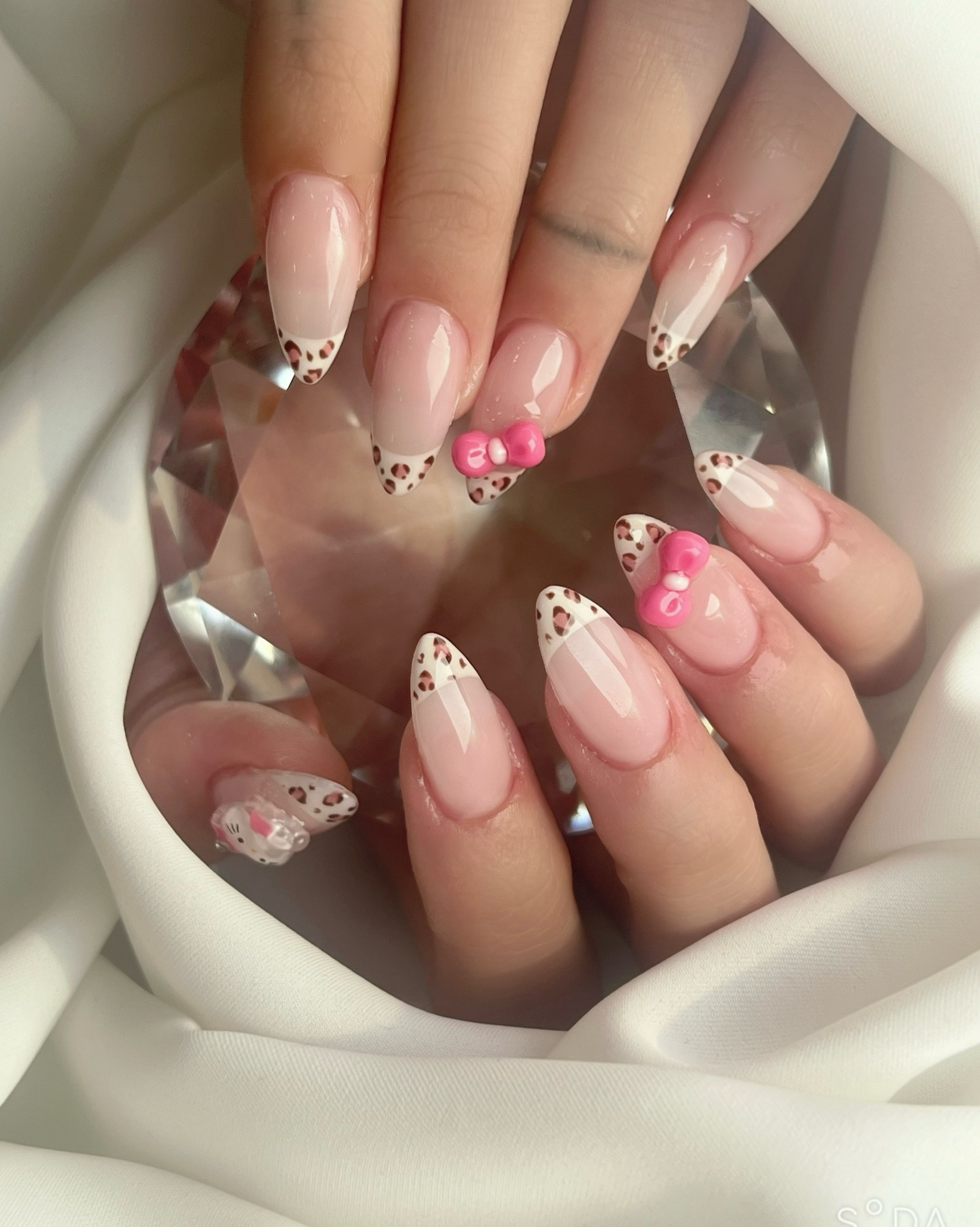 French-tip leopard print nail art with pink 3D ribbon accents