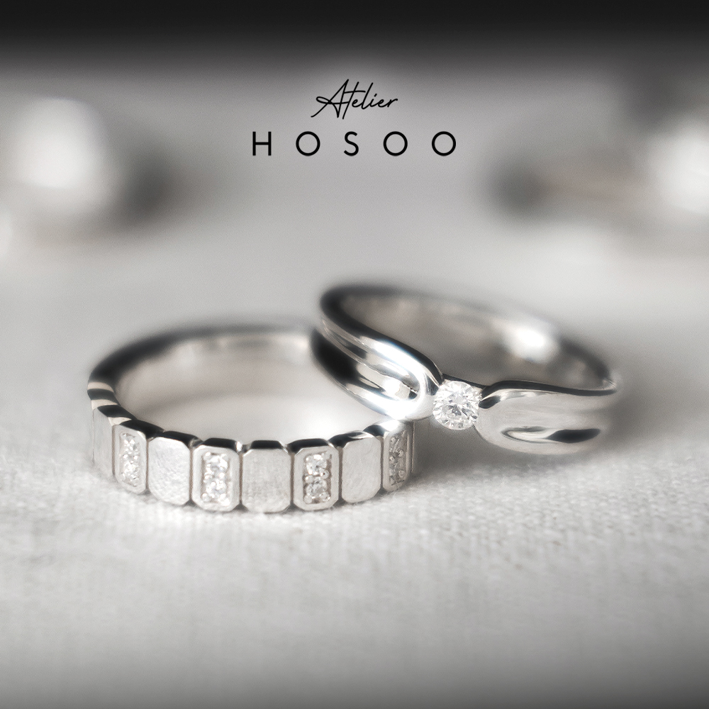 Two silver rings with gemstone accents on textured white fabric