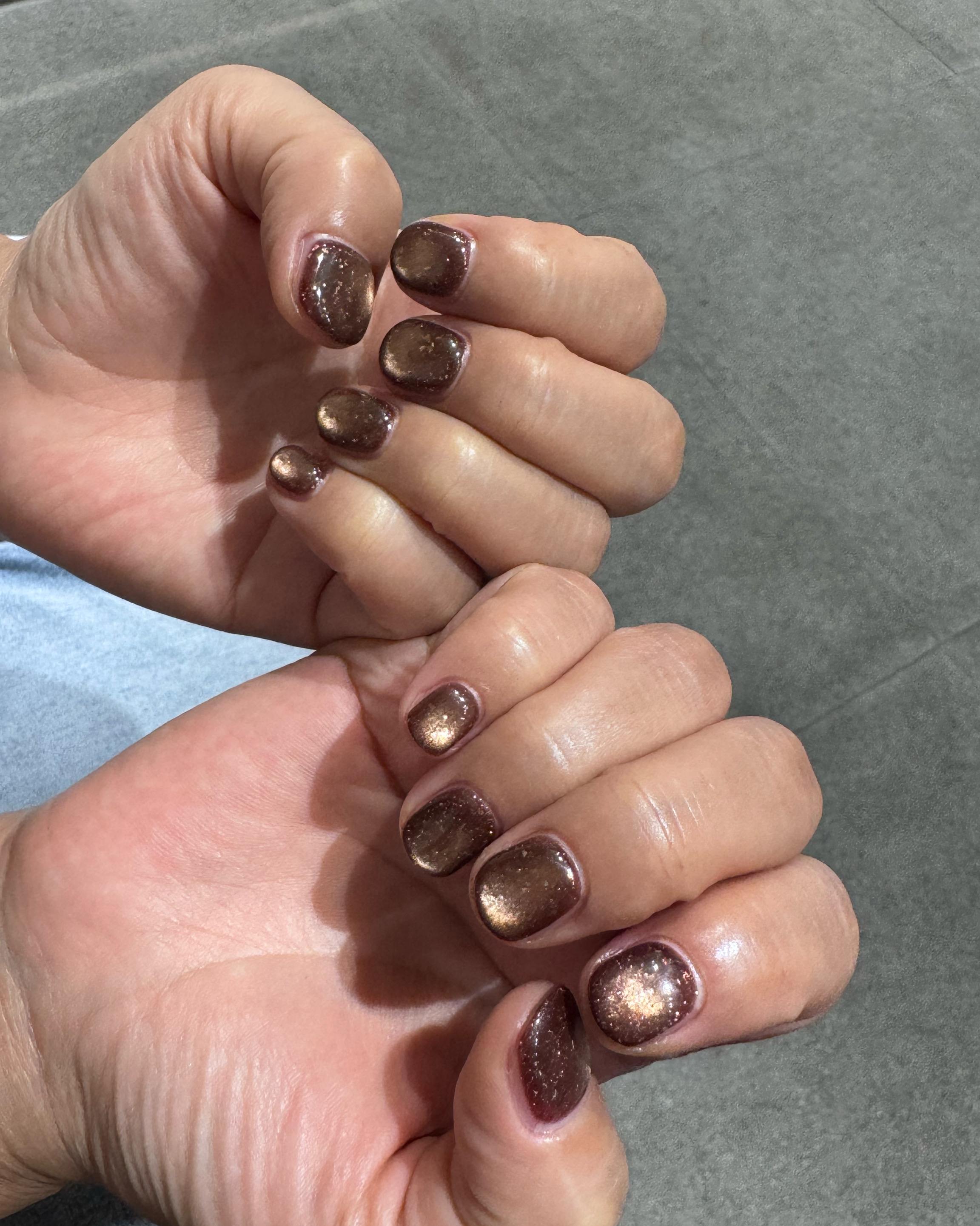 Short rounded nails featuring metallic bronze glitter polish