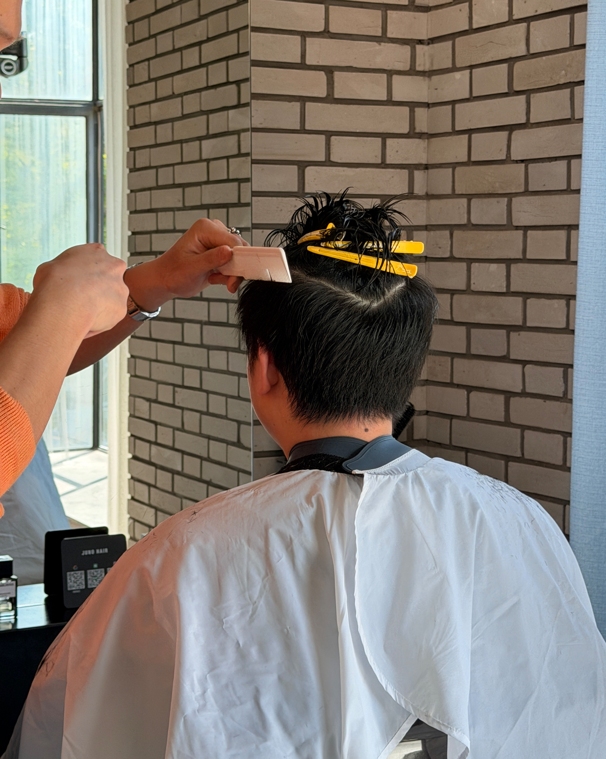 Stylist performing precision haircut with comb and sectioning clips