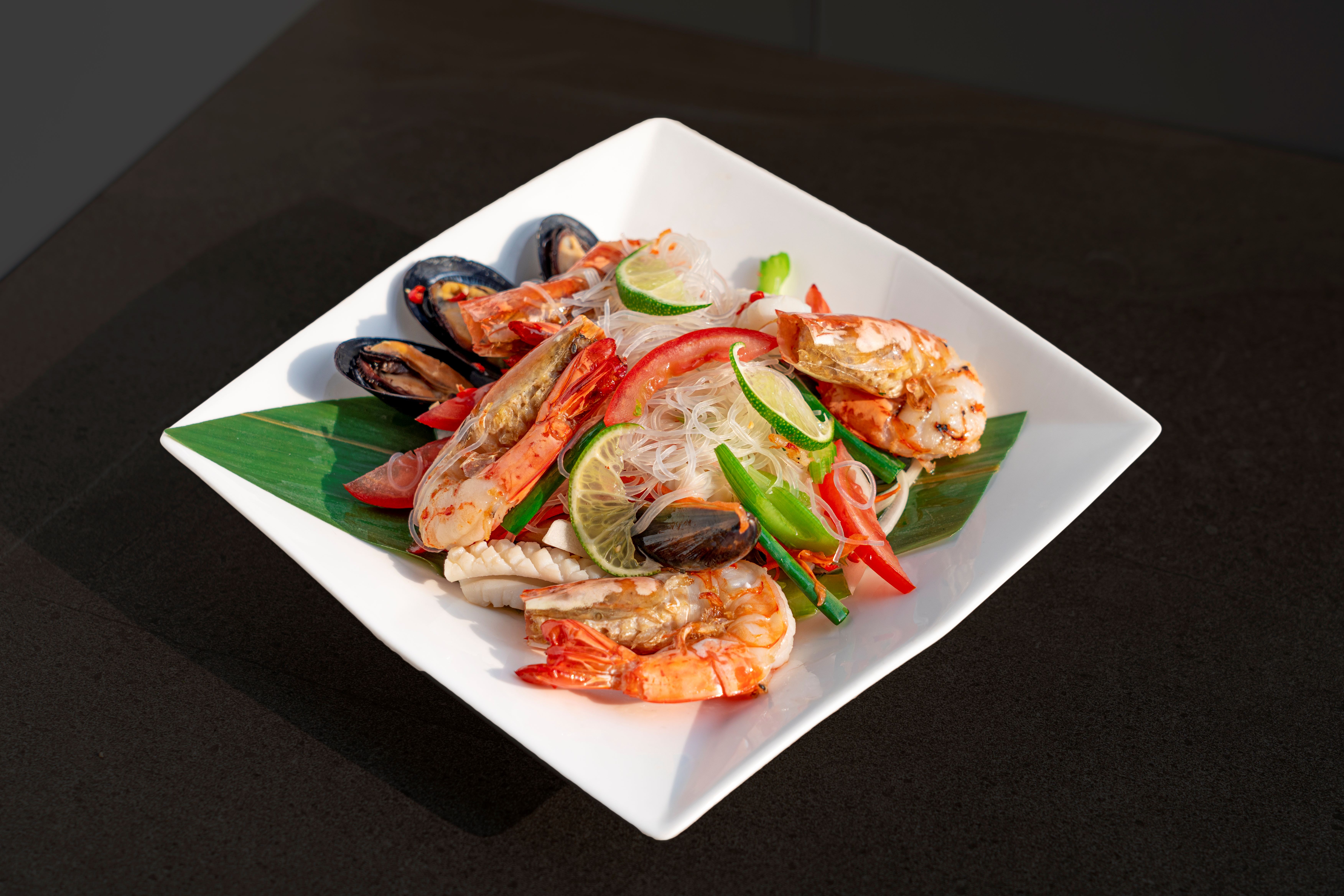 Yum Woon Sen seafood glass noodle salad plated with fresh lime and prawns
