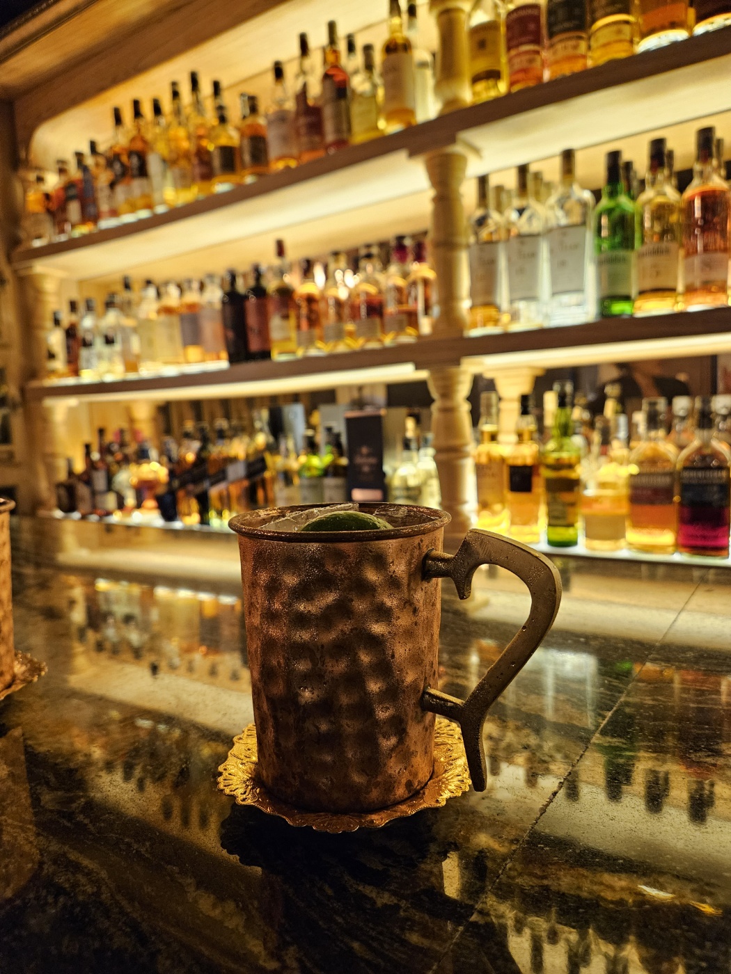 Moscow Mule cocktail in a hammered copper mug resting on an ornate brass coaster