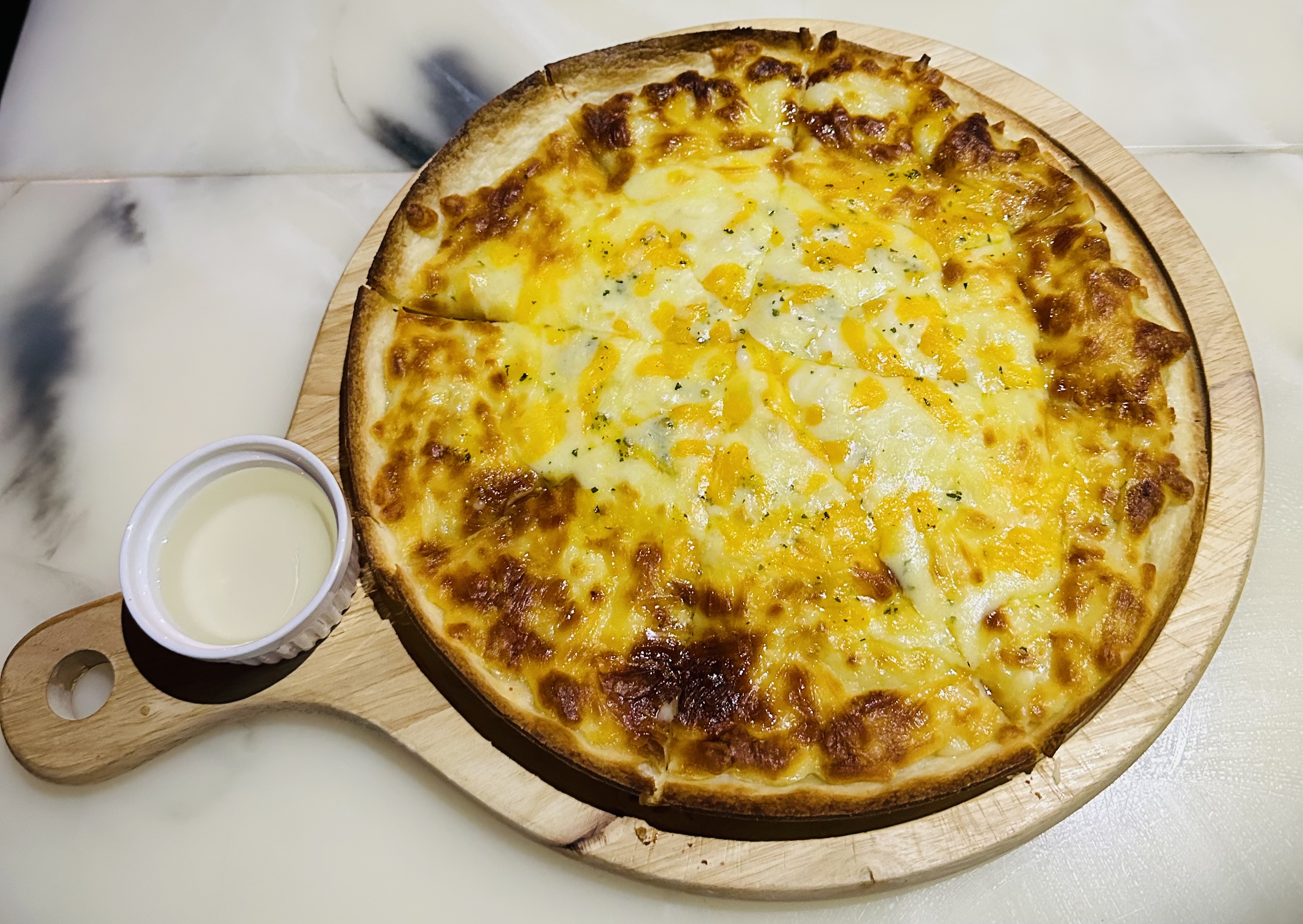 Thin crust cheese pizza on wooden paddle