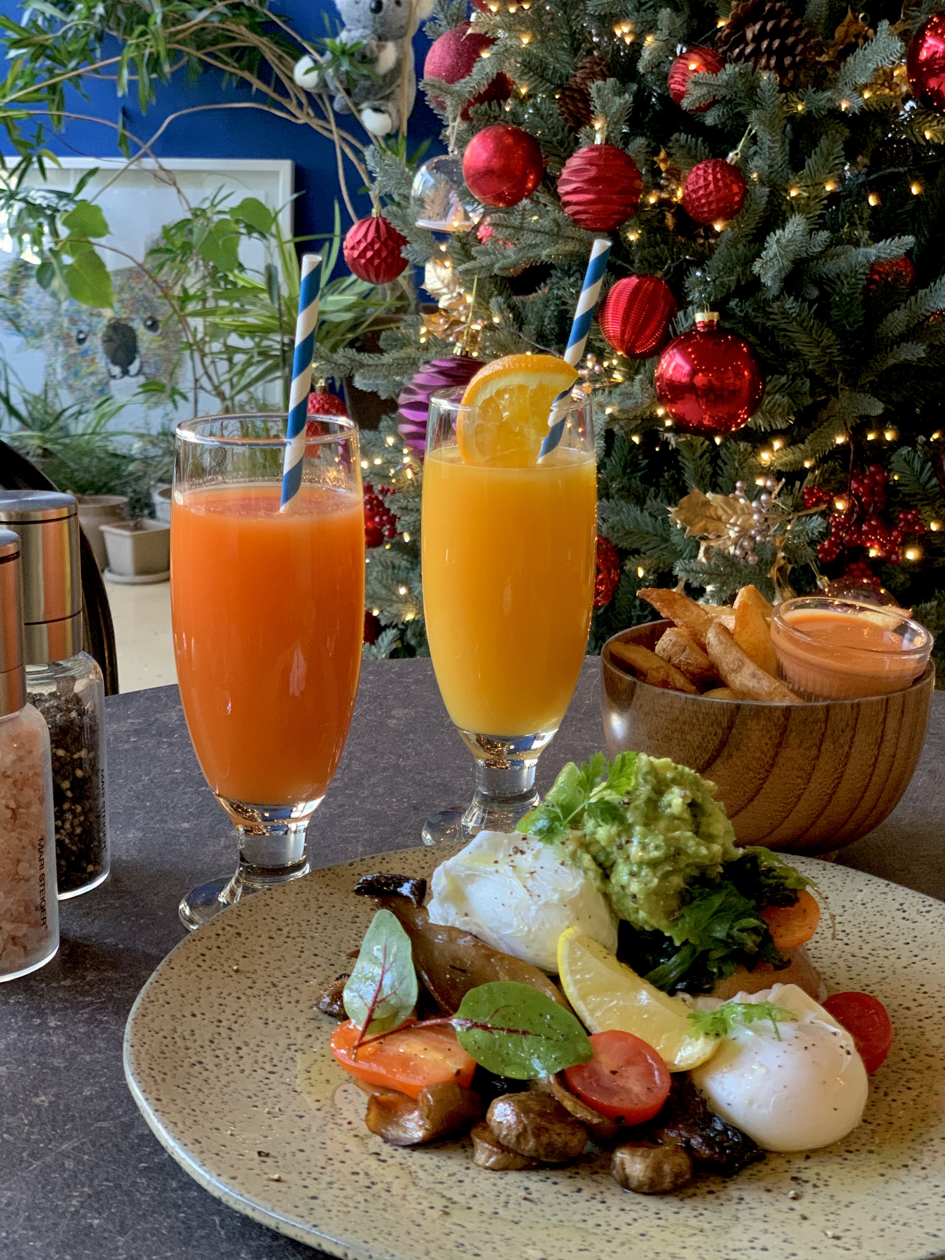 Brunch dishes including poached eggs and avocado on a plate next to fruit juice glasses.
