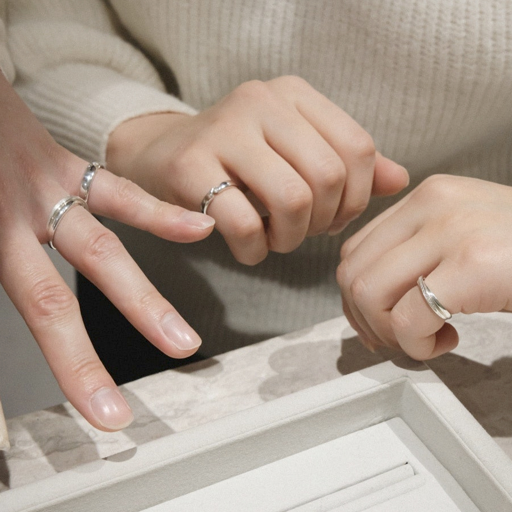 Hands wearing handcrafted silver rings at a jewelry workshop