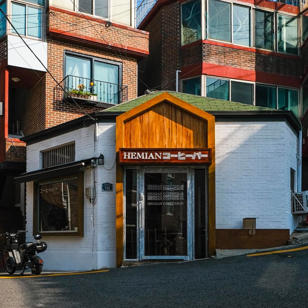 Exterior facade of Hemian Coffee Bar with white brick and wood frame entrance