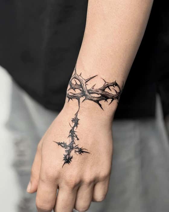 Crown of thorns and cross tattoo wrapping wrist and hand