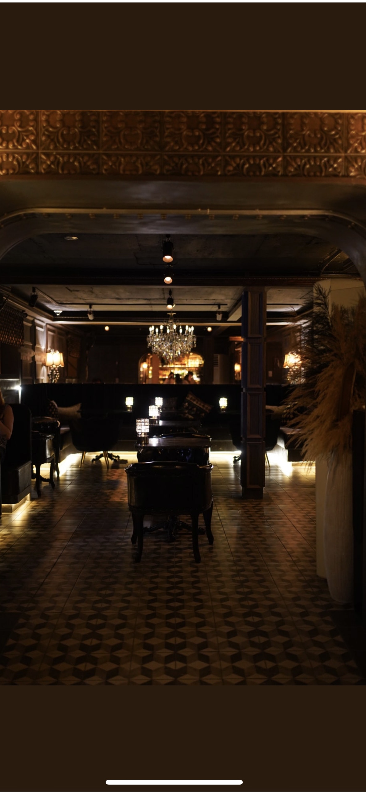 Interior lounge seating area with warm ambient chandelier and patterned tile floor