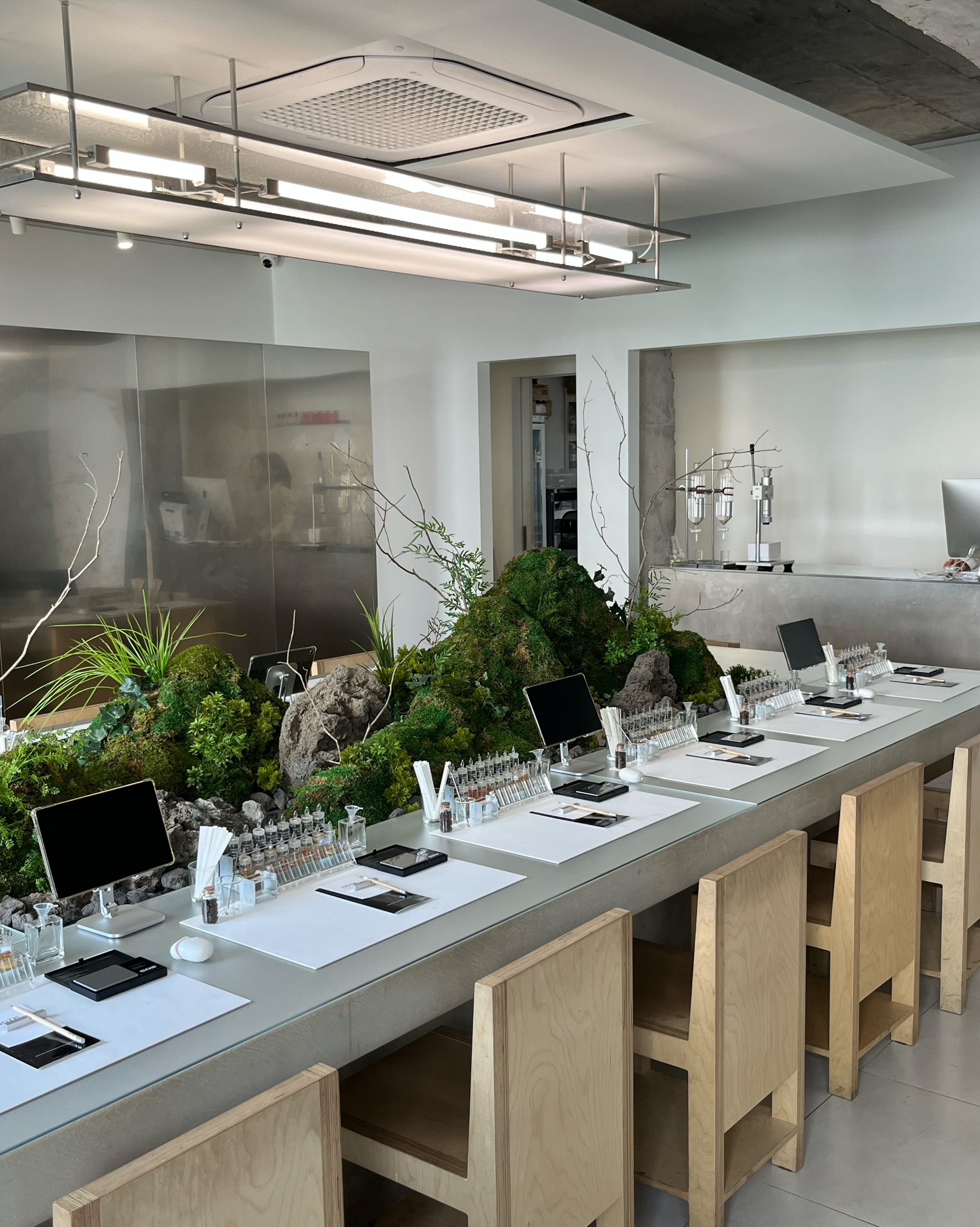 Minimalist workshop tables lined with digital tablets and mossy rock installations