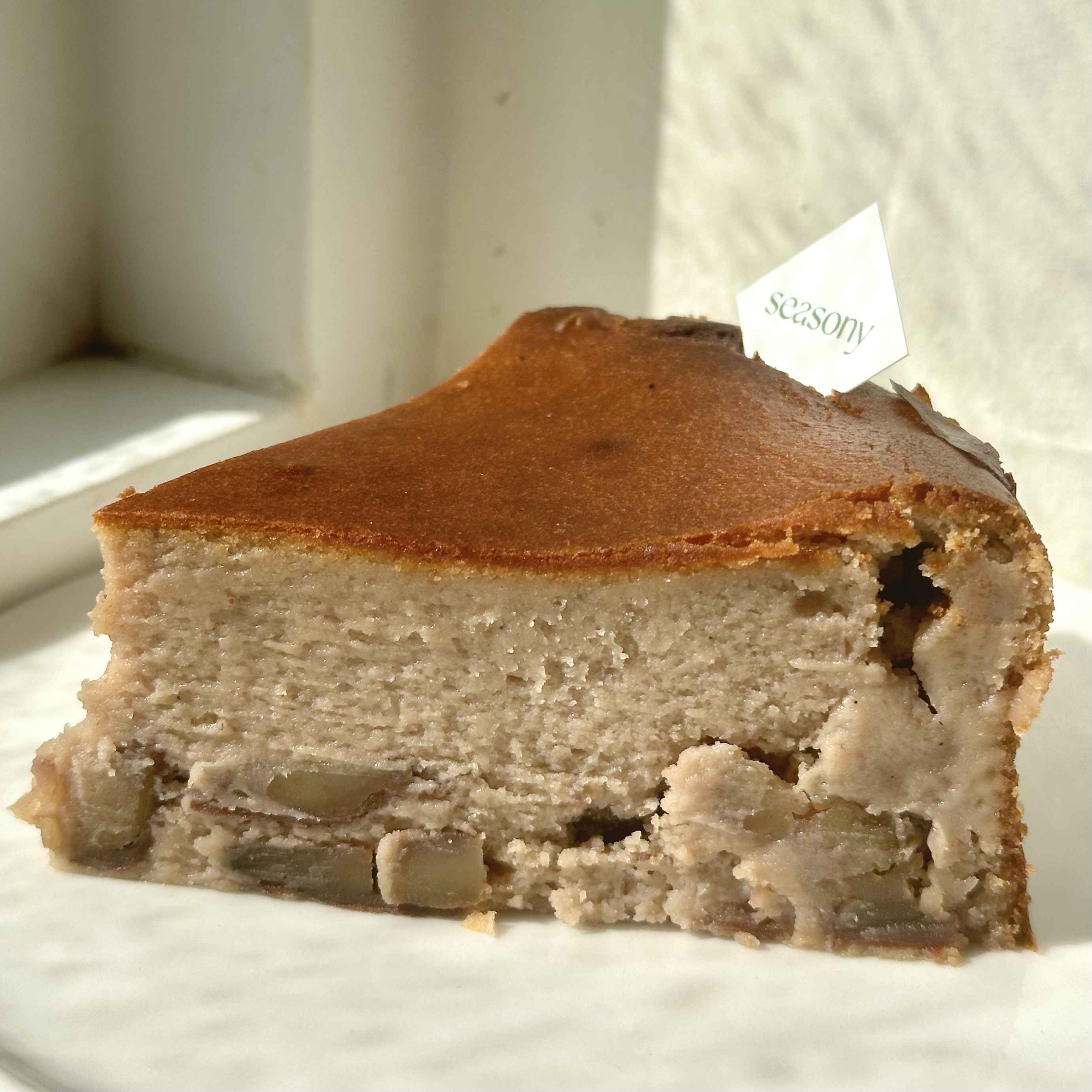 Slice of chestnut basque cheesecake showing dense cream cheese body and charred top