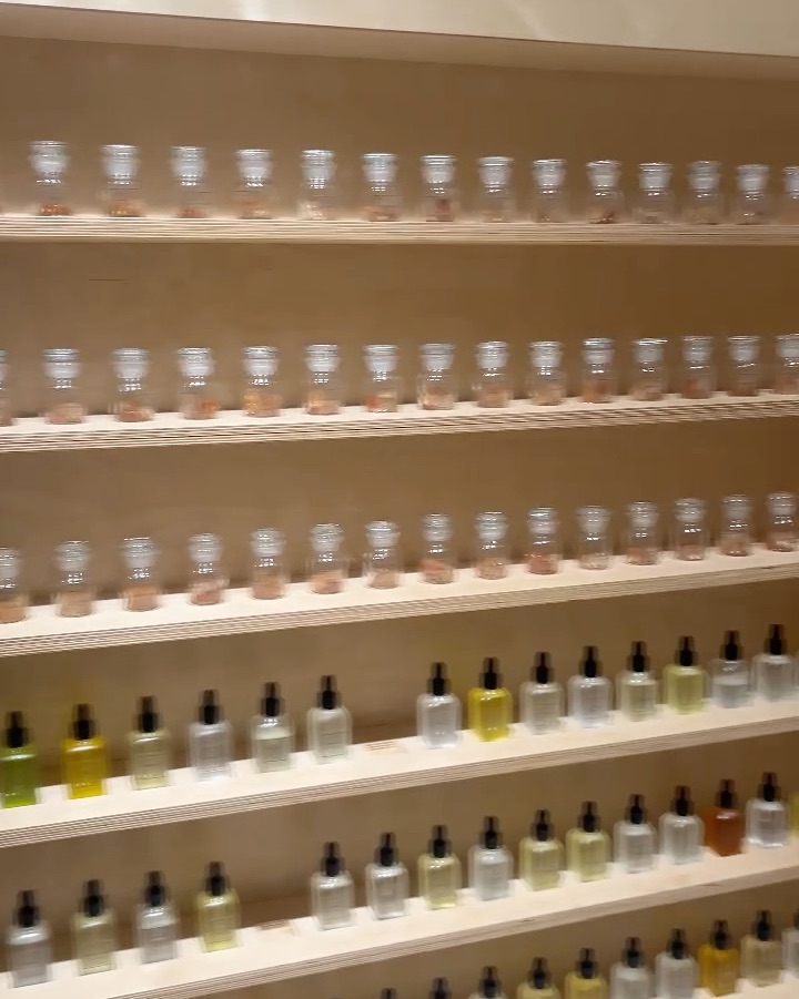 Neat horizontal wooden shelving filled with categorized perfume glass vials