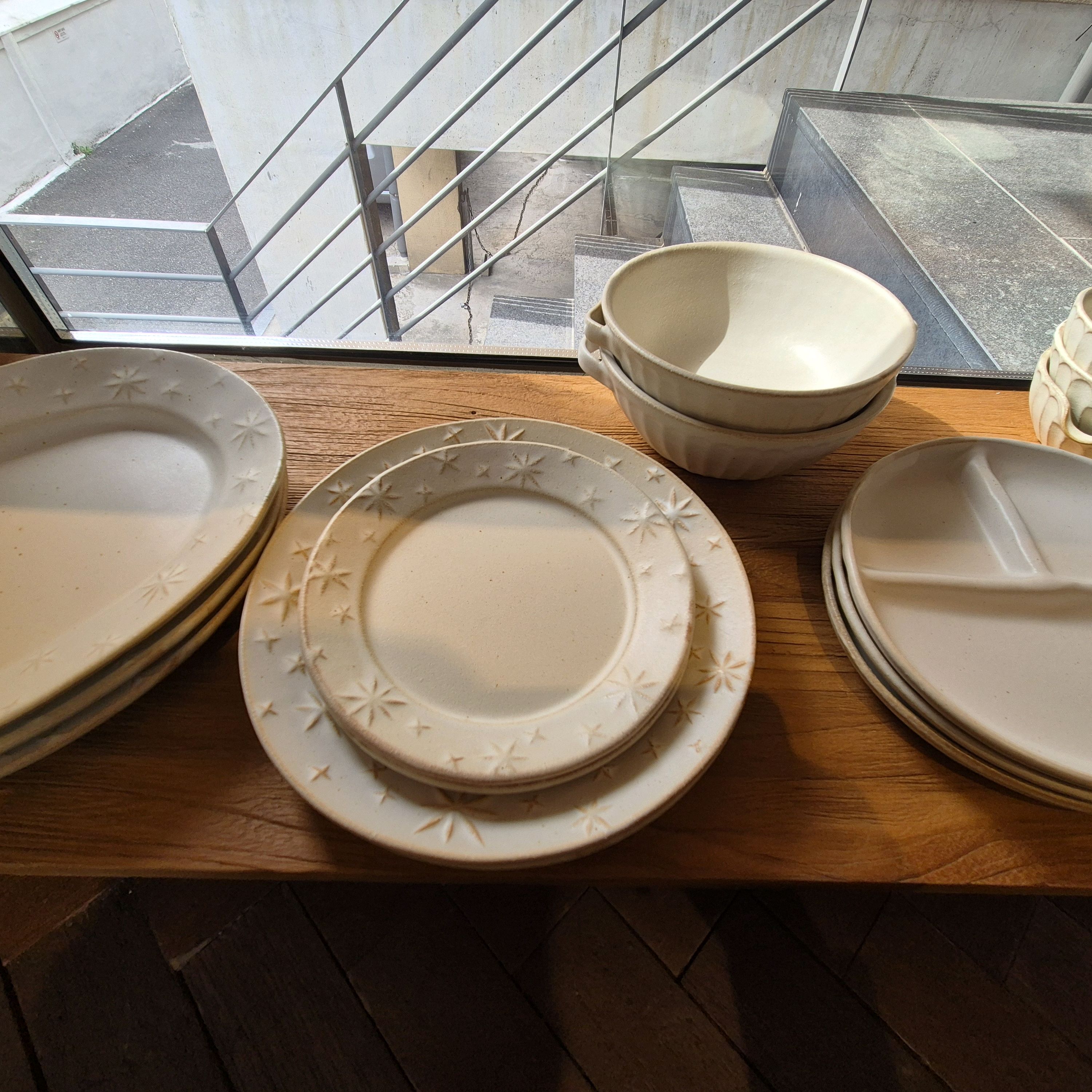 Stacks of artisanal ceramic plates with star patterns near a window.