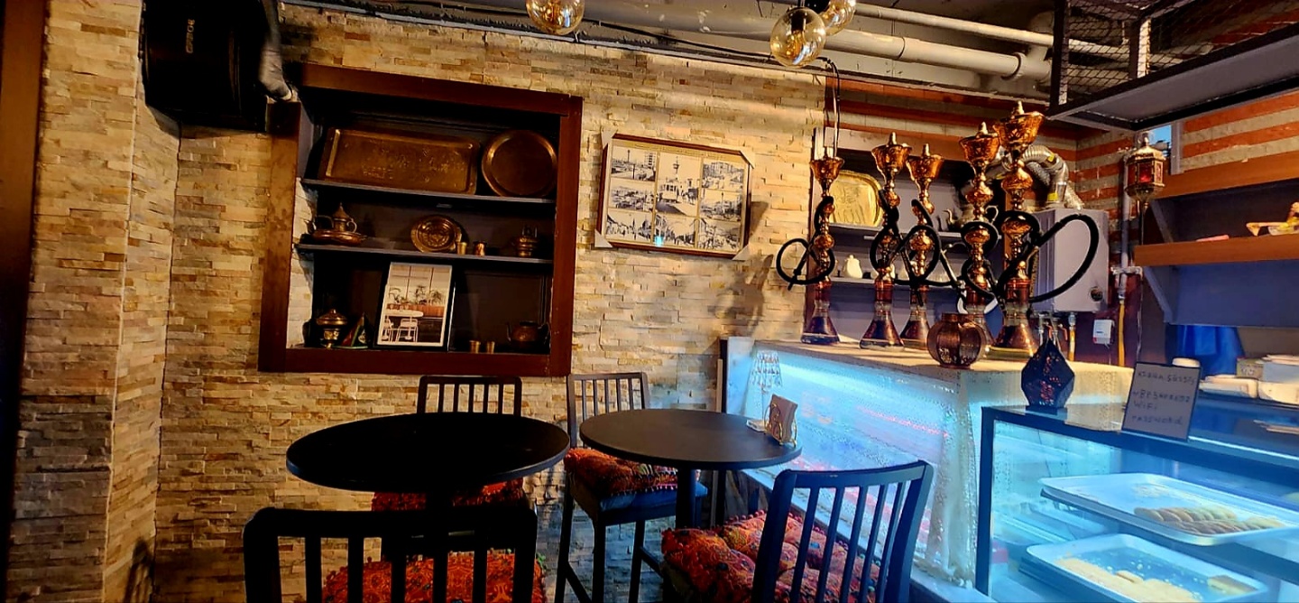 Interior dining corner with stacked stone wall and shisha lounge display