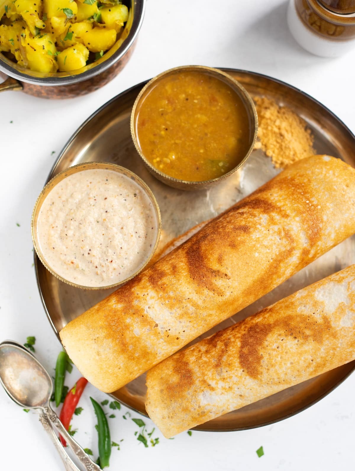 Traditional South Indian dosa platter served with fresh coconut chutney and potato masala on brassware