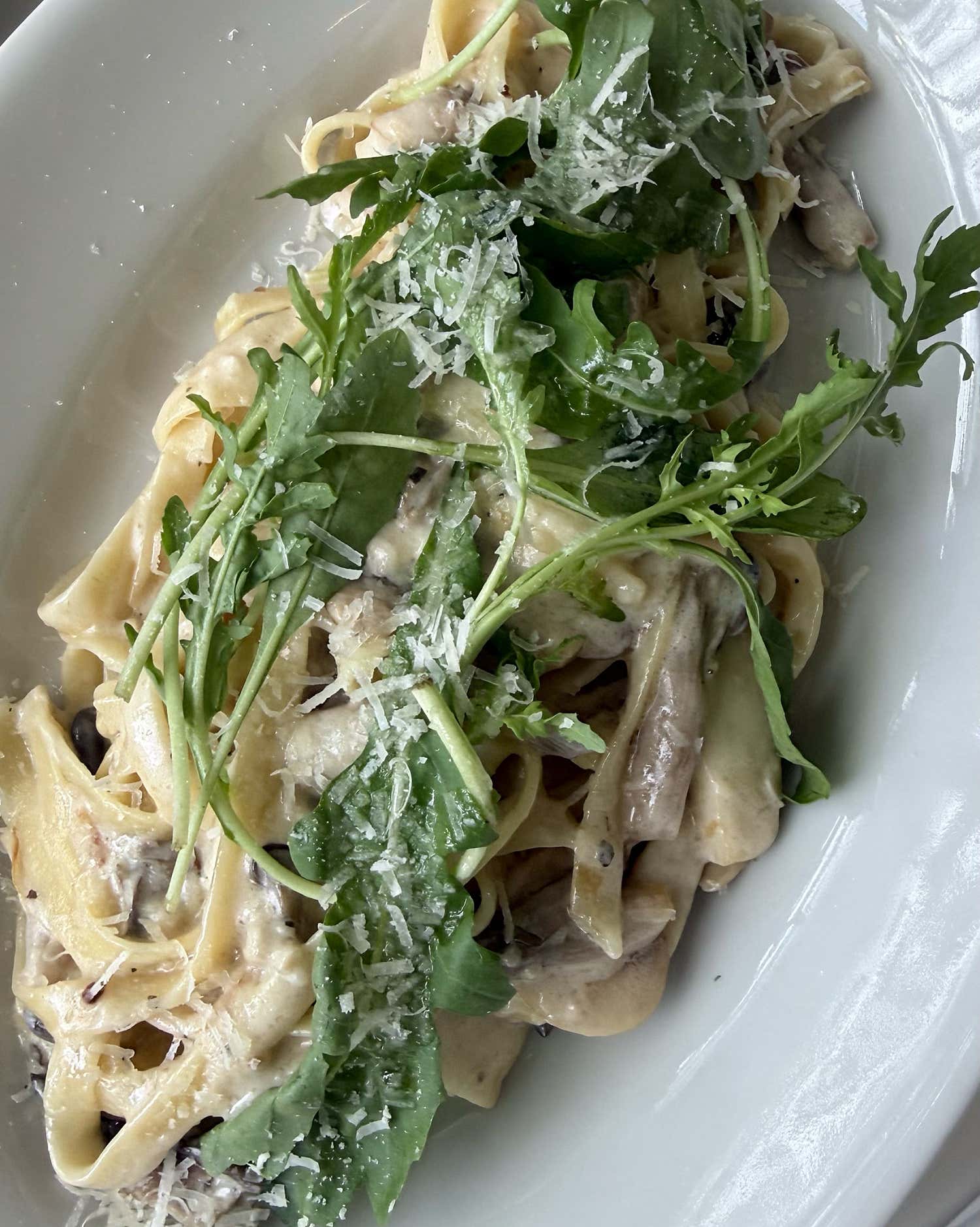 Creamy mushroom fettuccine pasta topped with fresh arugula and shredded cheese