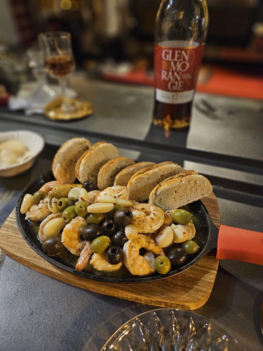 Sizzling shrimp ajillo in a cast iron skillet served with toasted baguette slices