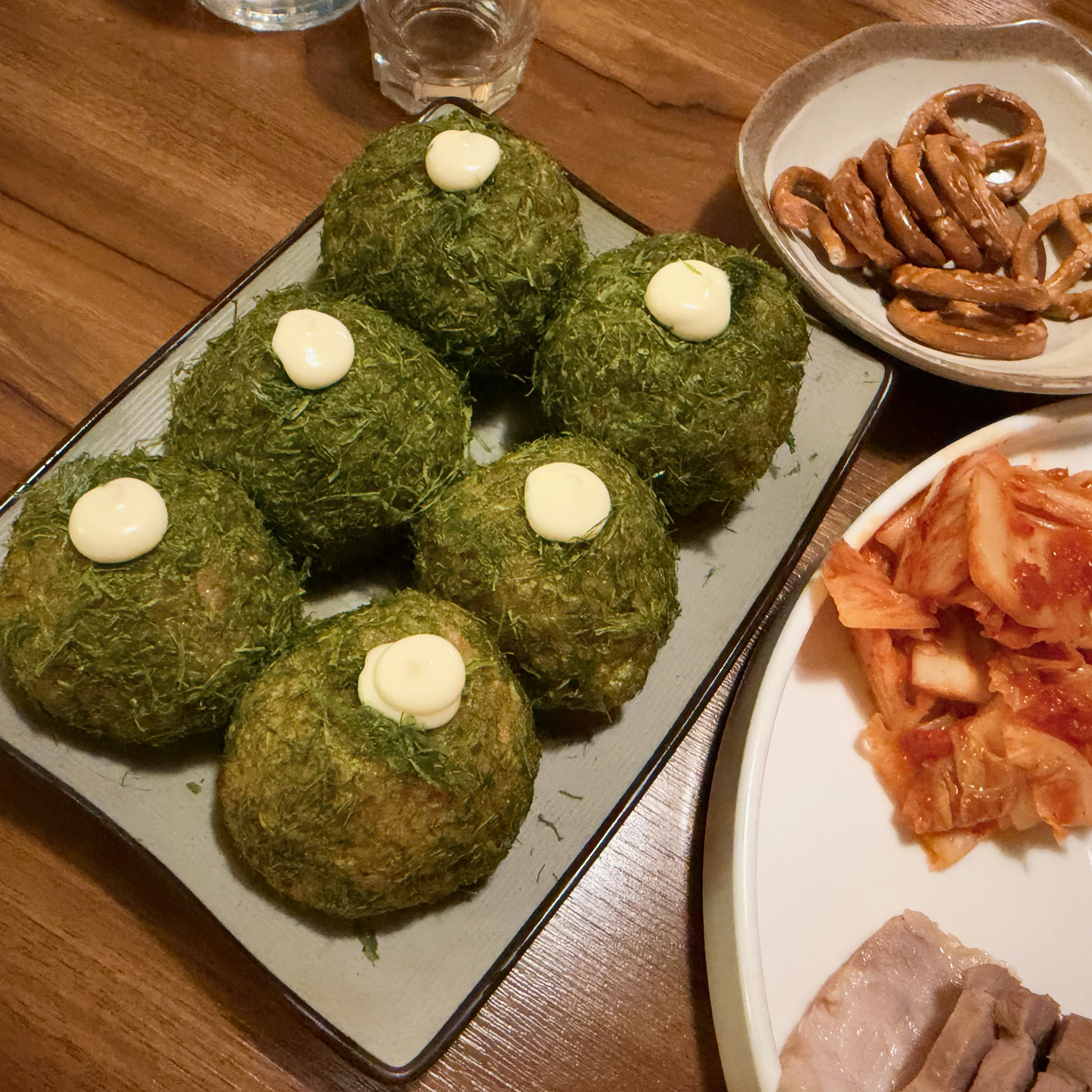 Handcrafted green seaweed rice balls topped with house white sauce