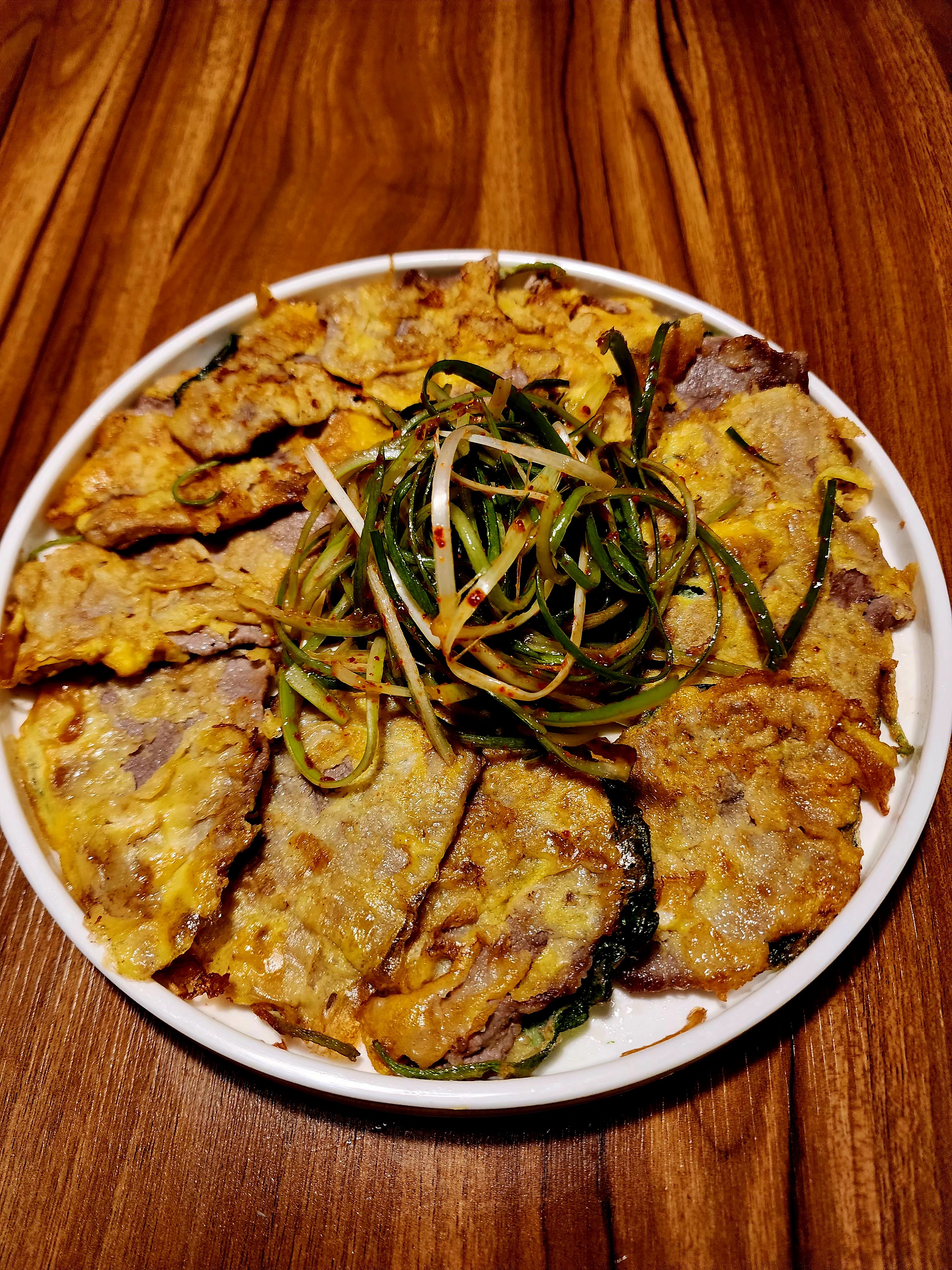 Pan-fried egg-battered beef pancakes topped with seasoned shredded scallions