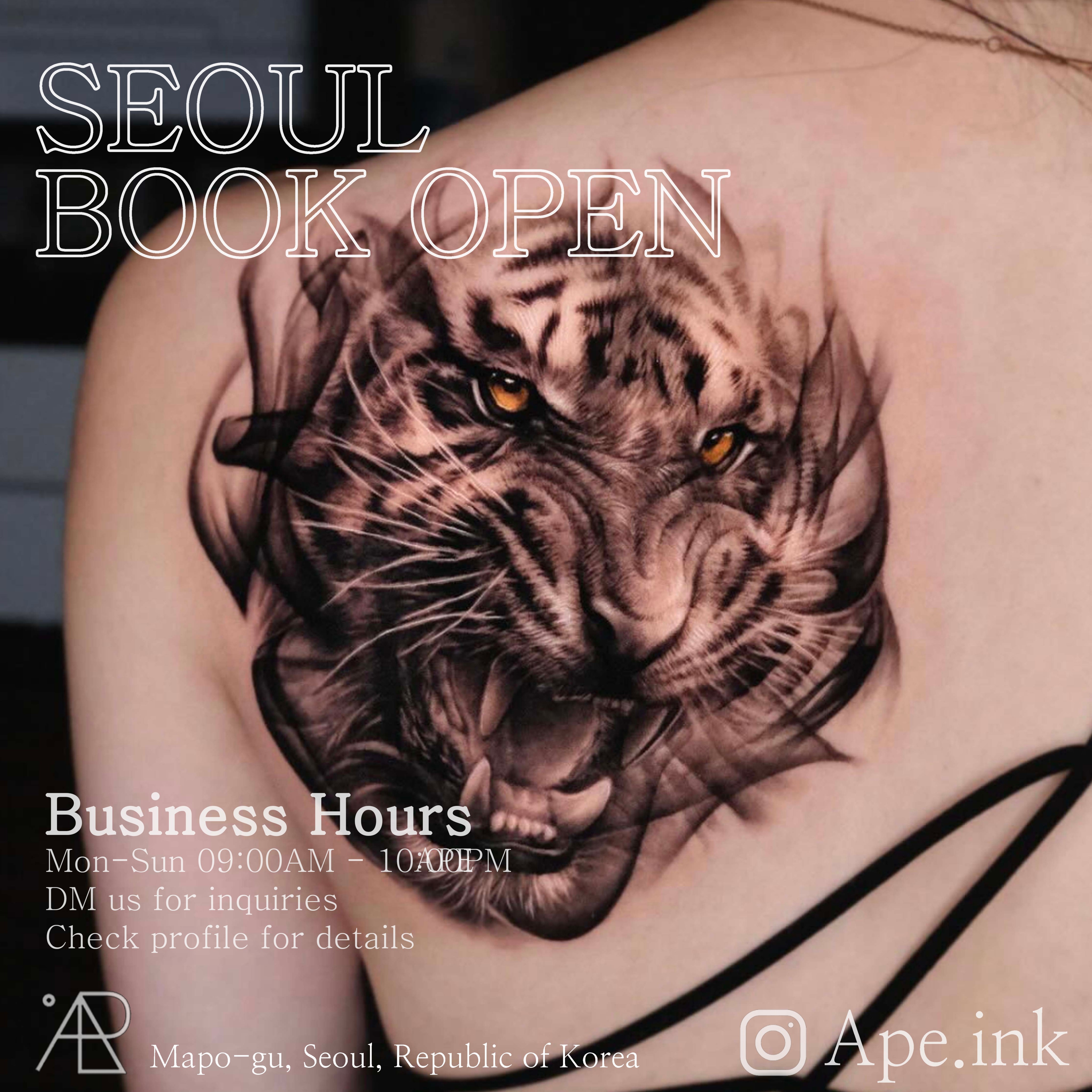 Realistic tiger back tattoo with detailed shading and glowing eye detail by Ape Ink Studio